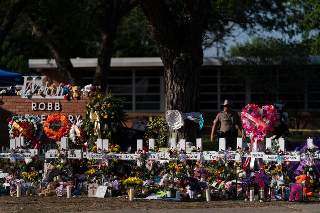 <p>Flowers and candles are placed around crosses on May 28, 2022, at a memorial outside Robb Elementary School in Uvalde, Texas</p>