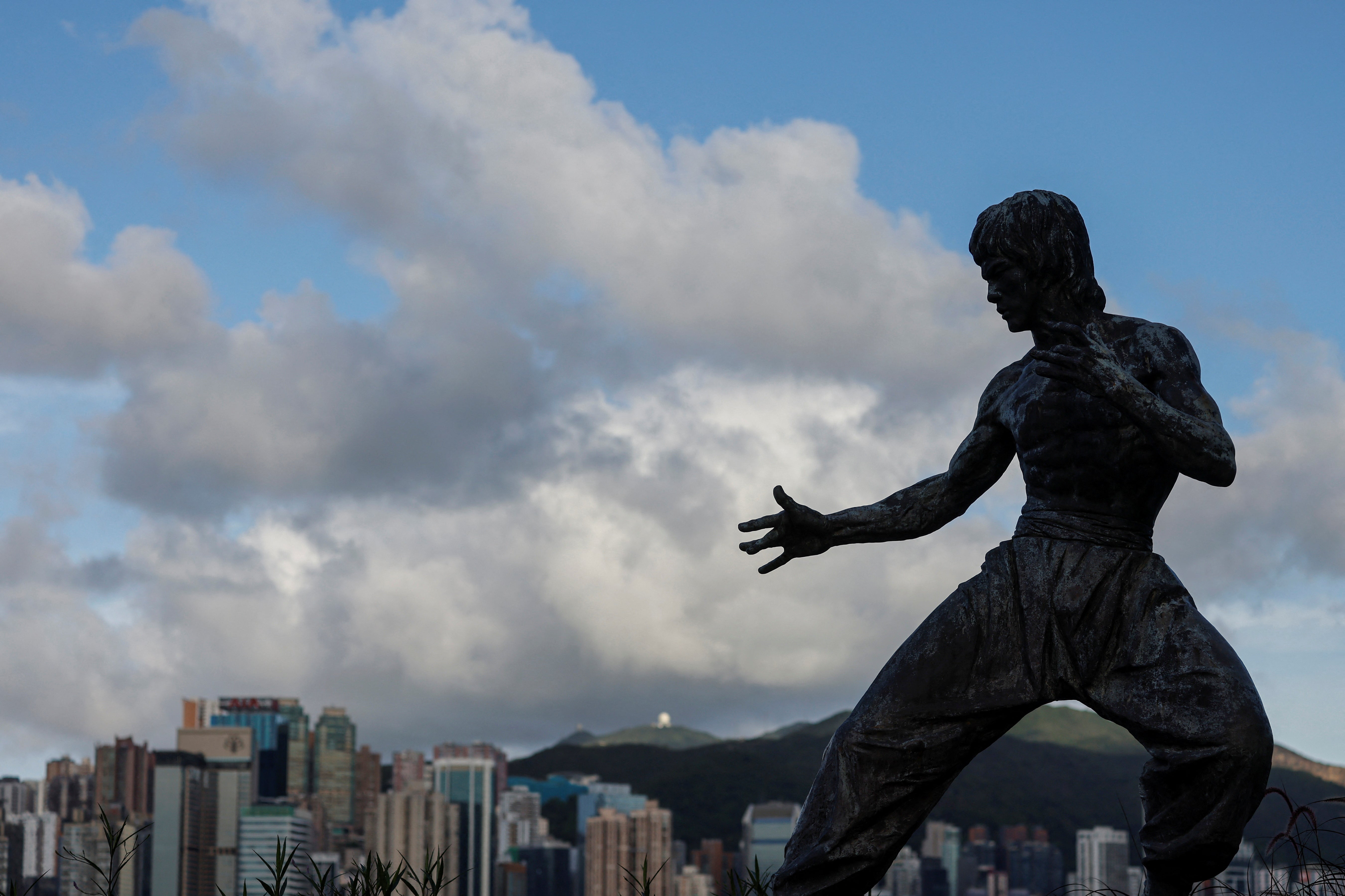 A statue of the martial artist and actor Bruce Lee is silhouetted against the skyline on the Avenue of Stars near the Tsim Sha Tsui waterfront