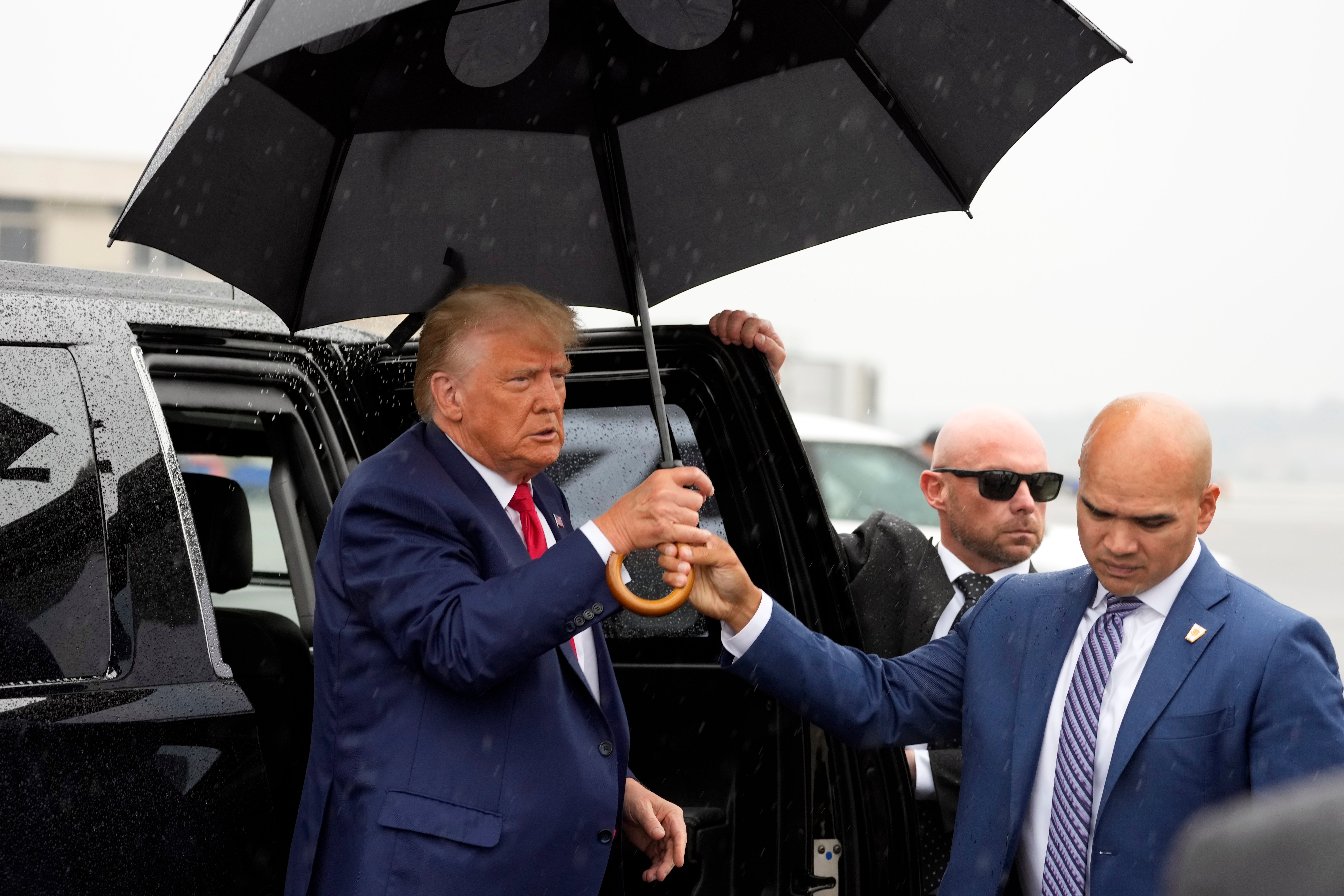 Valet Walt Nauta hands former Donald Trump an umbrella before he speaks at Ronald Reagan Washington National Airport in 2023
