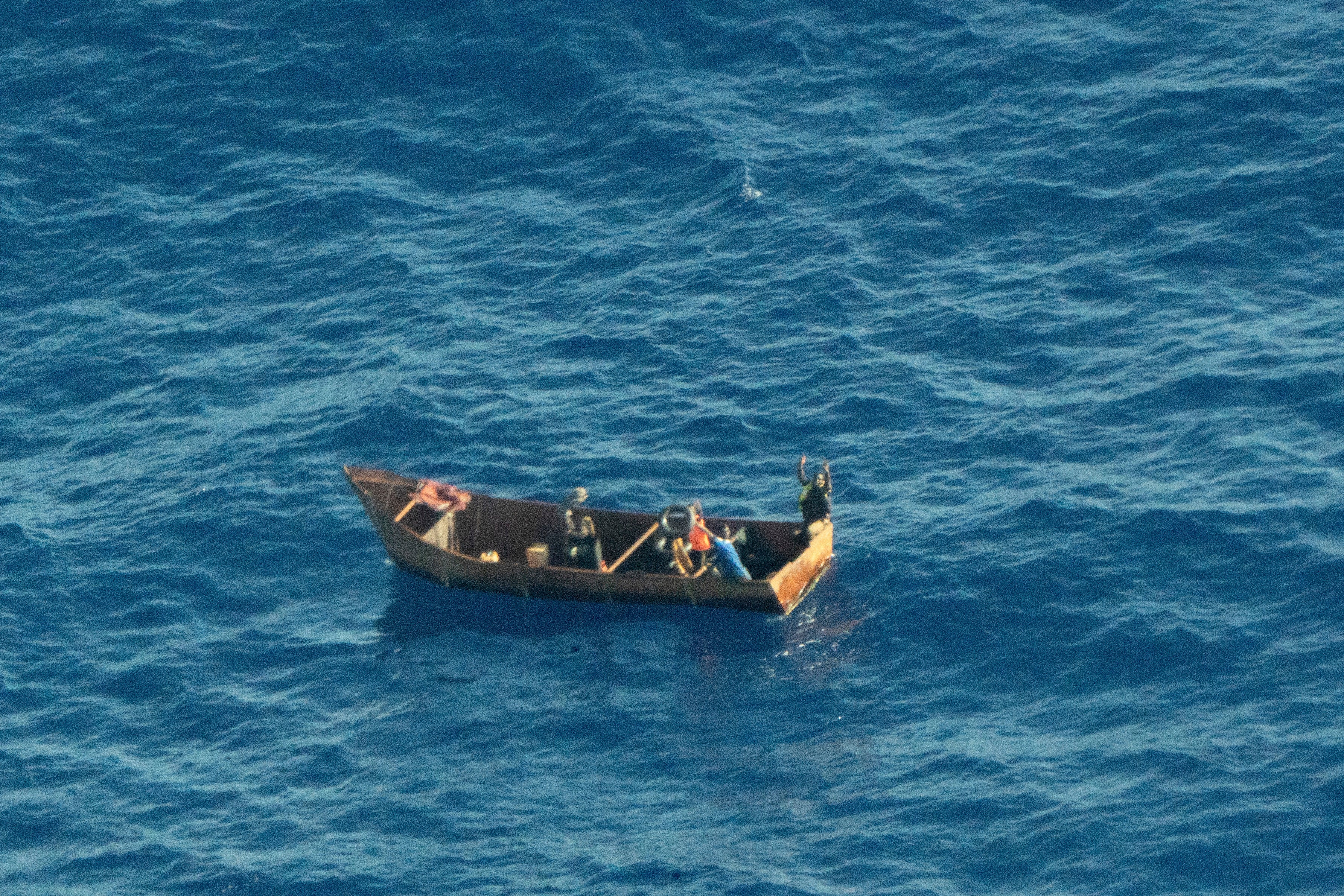 In this photo provided by Sea-Watch on Tuesday, August, 8, 2023, four migrant survivors wave for help as they are in distress at sea