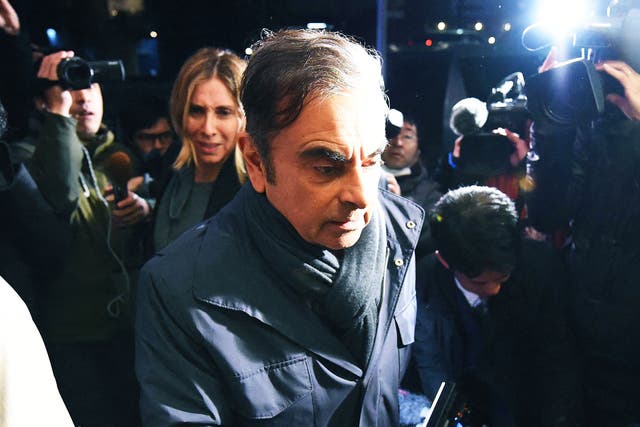<p>The former Nissan-Renault CEO Carlos Ghosn, followed by his wife Carole, is escorted to his Tokyo home in 2019</p>