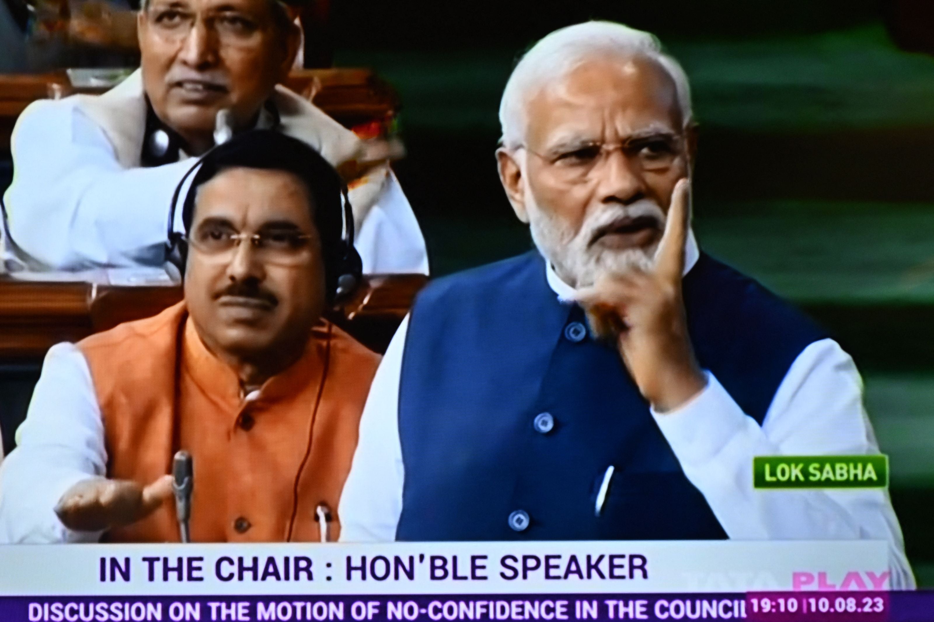In this screen grab India’s Prime Minister Narendra Modi (right) is seen on a television screen as he addresses the lower house Lok Sabha in New Delhi on 10 August 2023