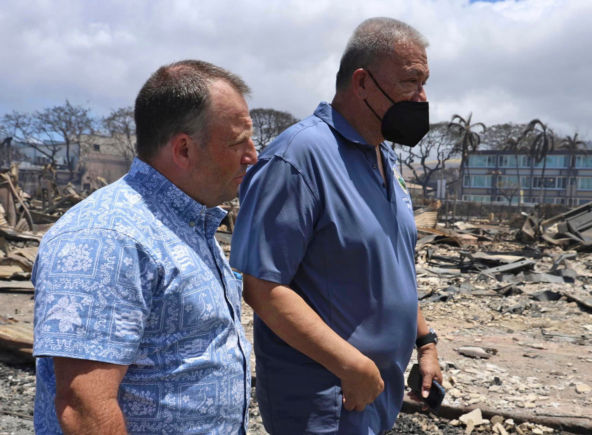 <p>Hawaii Governor Josh Green, left, and Mayor Richard Bissen walk past the burned remains along Front Street in Lahaina</p>