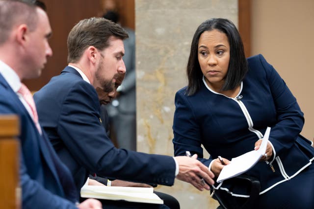 <p>Fulton County District Attorney Fani Willis, right, speaks with a member of her team in May 2022. </p>