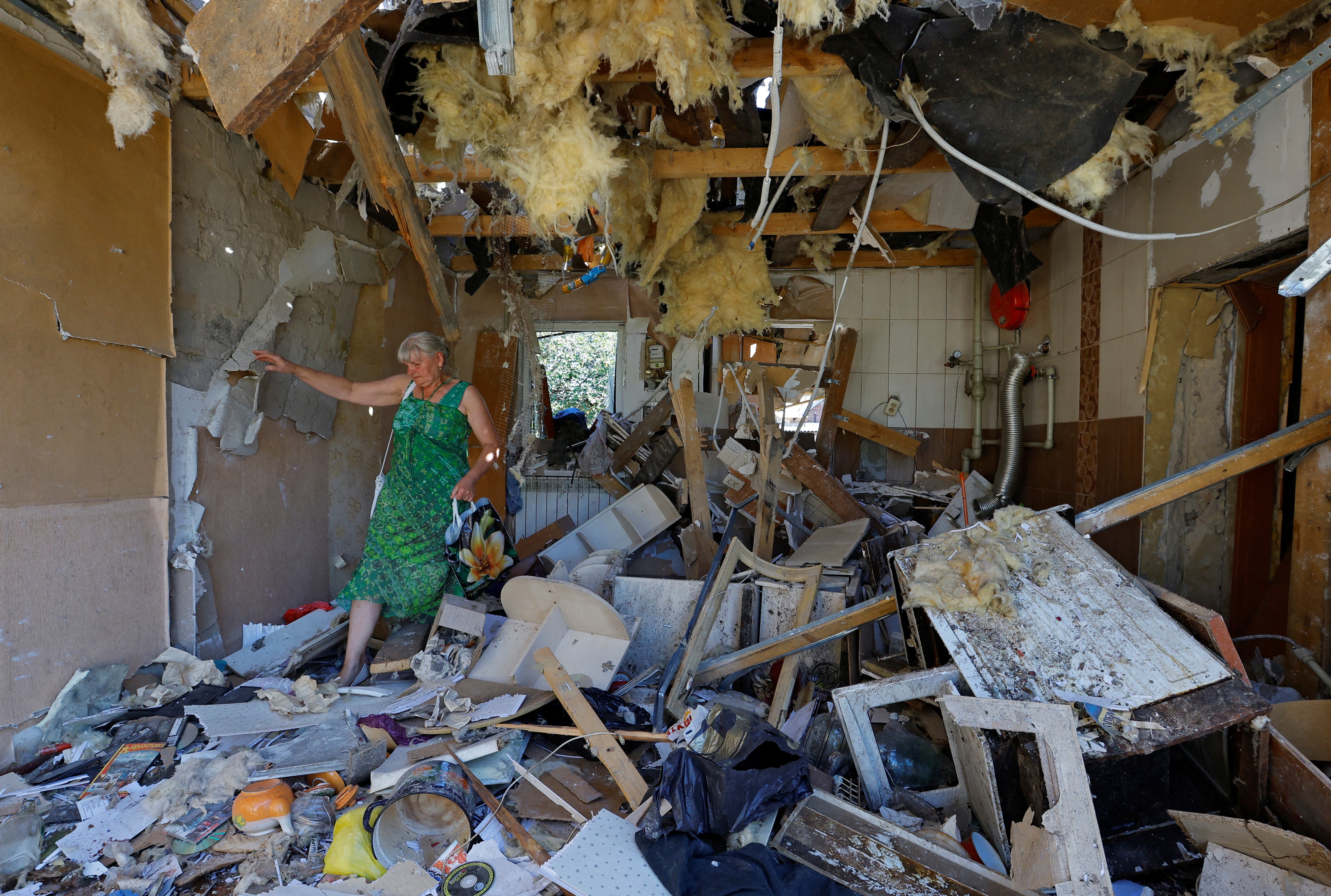 Lyubov Tolchina walks through the damaged house of her son Vitaly who was killed the day before by shelling in Donetsk