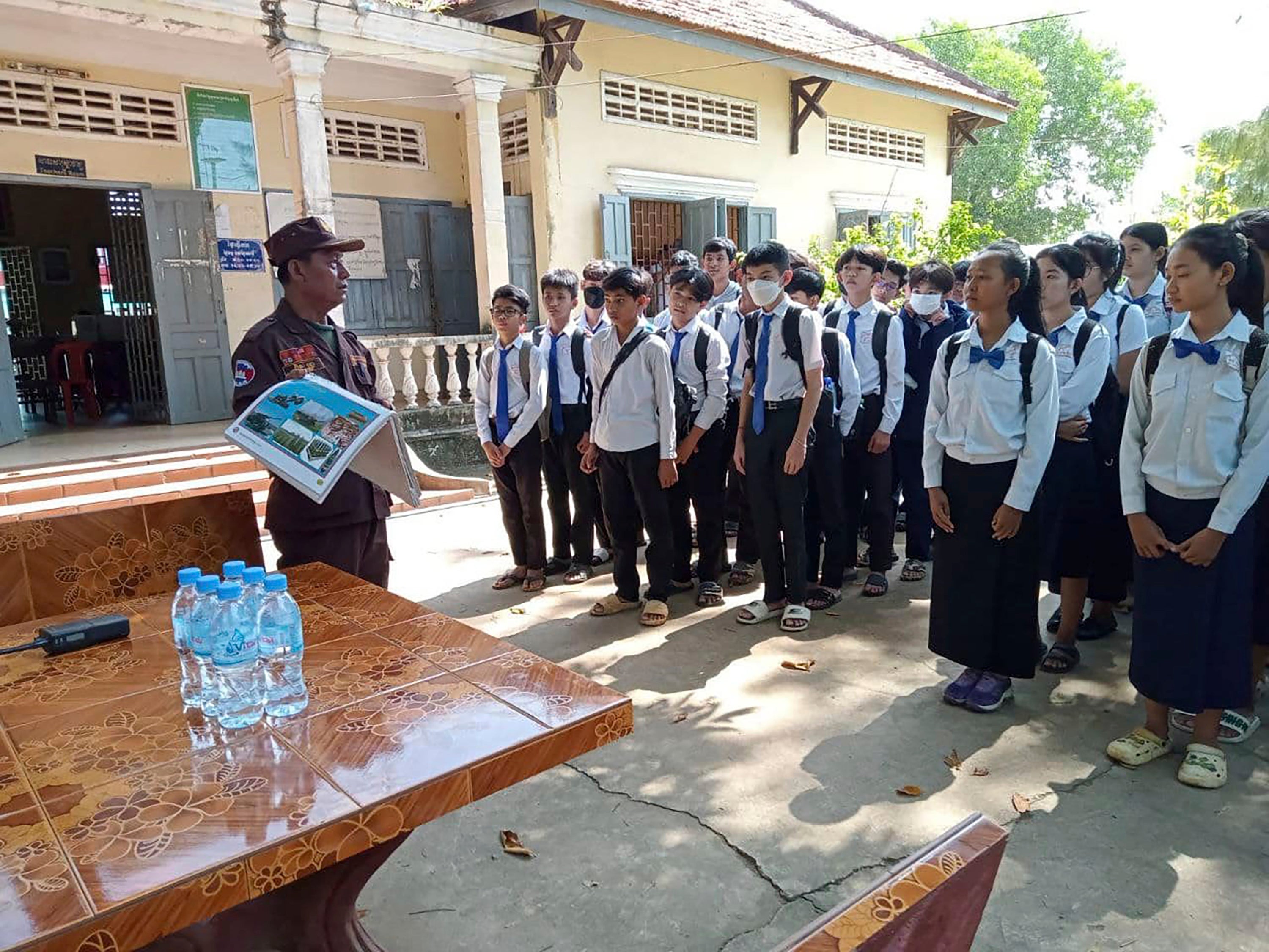 A deminer expert (left) instructs students at Queen Kossamak High School