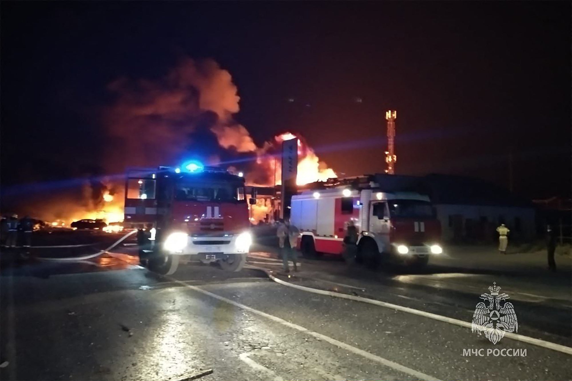 This handout photograph taken and released by Russian Emergency Ministry on 14 August 2023, shows rescuers pushing out a fire at a gas station in the city of Makhachkala