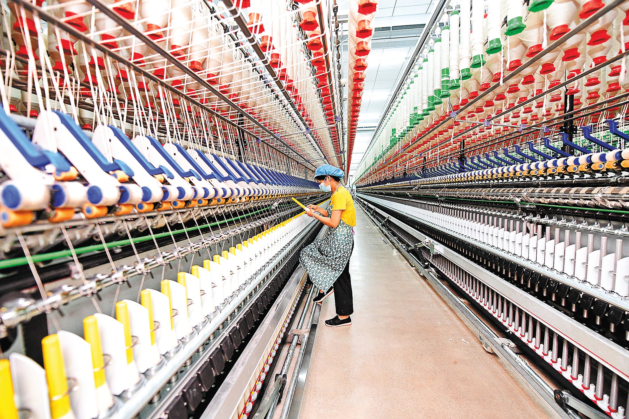 An employee works on a cotton yarn production line at an intelligent mechanised workshop of a textile company in Ganzhou, Jiangxi province, in May 2022