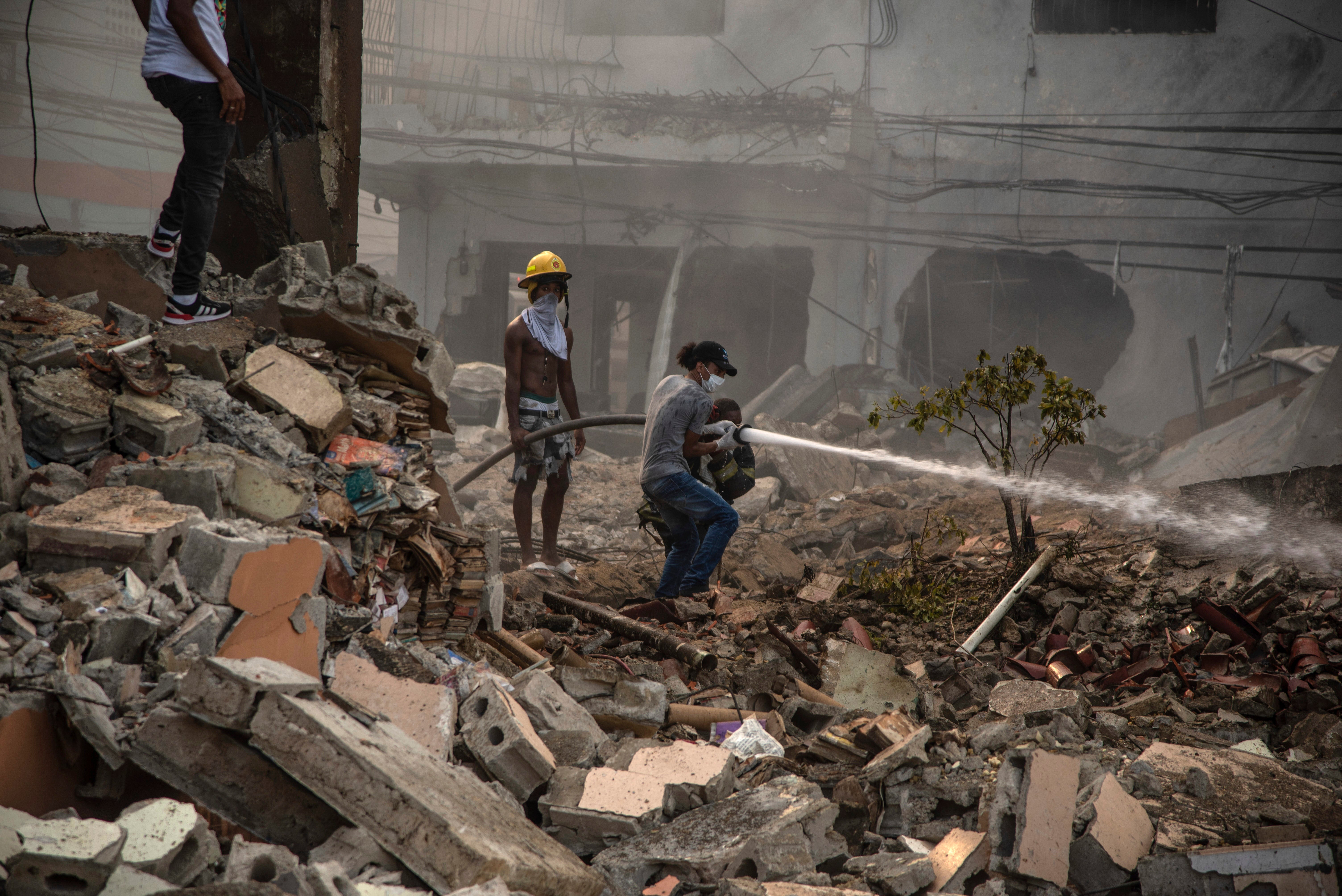 Firefighters put out a fire after a powerful explosion in San Cristobal, Dominican Republic, Monday, Aug 14, 2023. The Monday afternoon explosion killed at least three people and injured more than 30 others, authorities said.