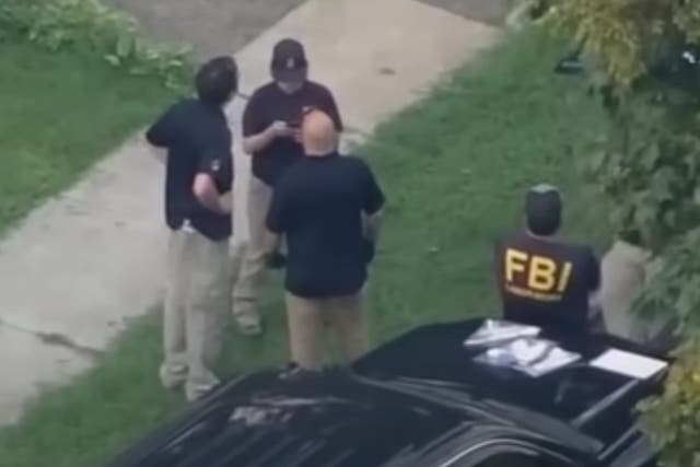 <p>FBI agents wait outside of the home of a 17-year-old who has been accused of communicating with extremist organisations and plotting a terror attack</p>