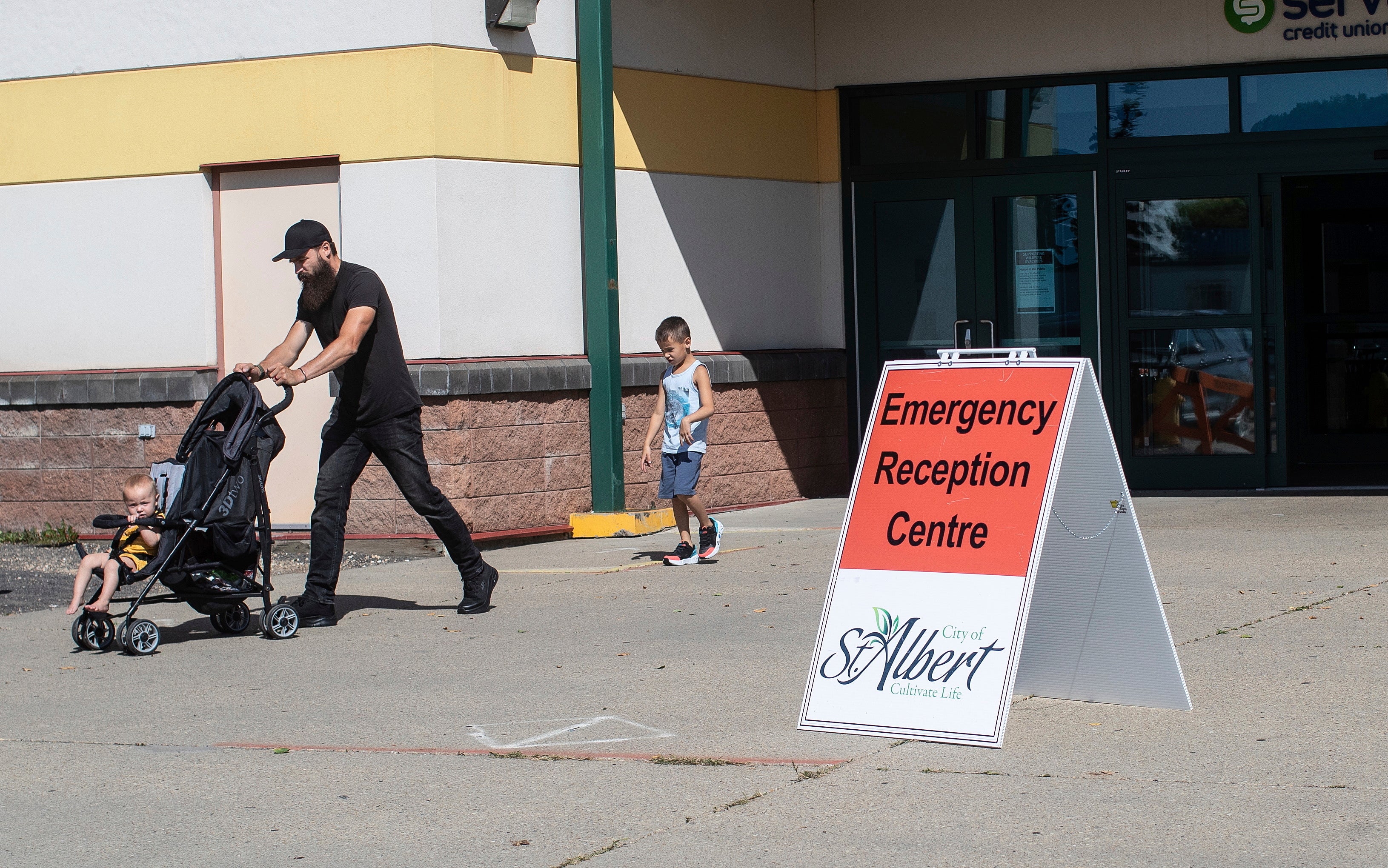 Wildfire evacuees walk out of the evacuee centre in St Albert, on Wednesday