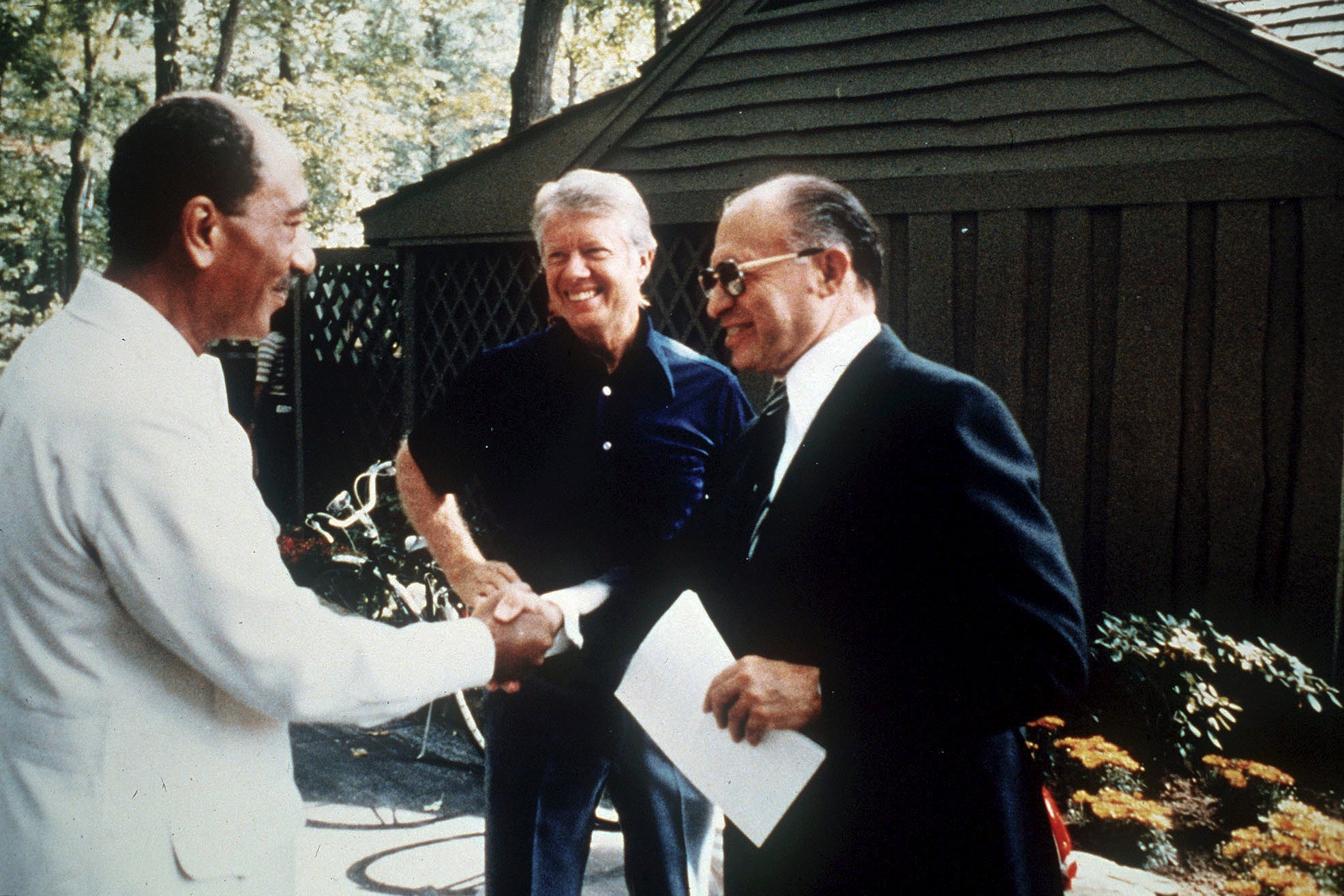 Egypt's president Anwar Sadat, left, shakes hands with Israeli prime minister Menachem Begin as US president Jimmy Carter, centre, looks on, at Camp David, September 1978