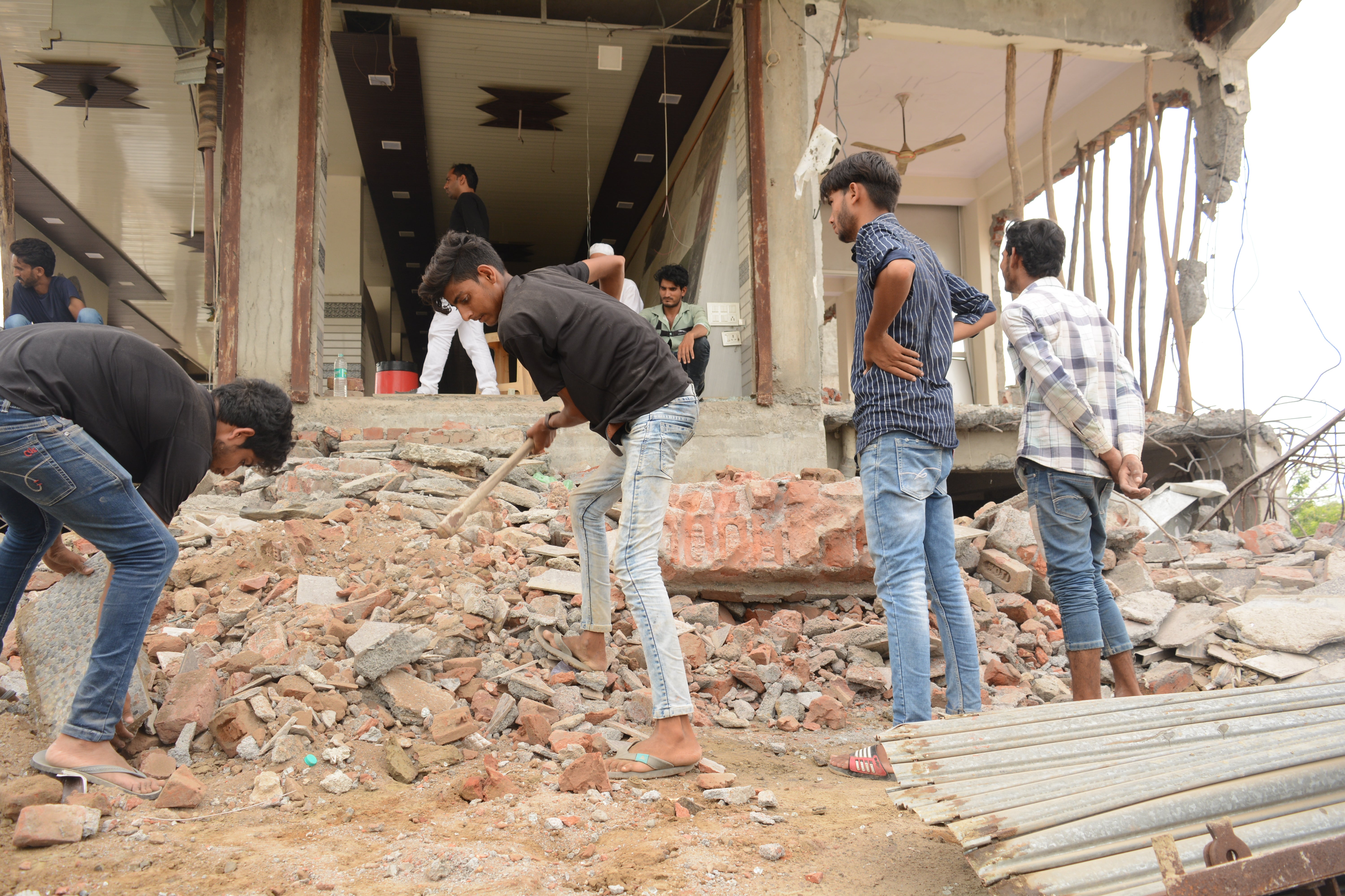 People clearing debris on 8 August 2023 after the authorities in Nuh bulldozed their homes