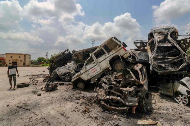 A man walks past burned vehicles after violent communal clashes in Nuh on 1 August 2023