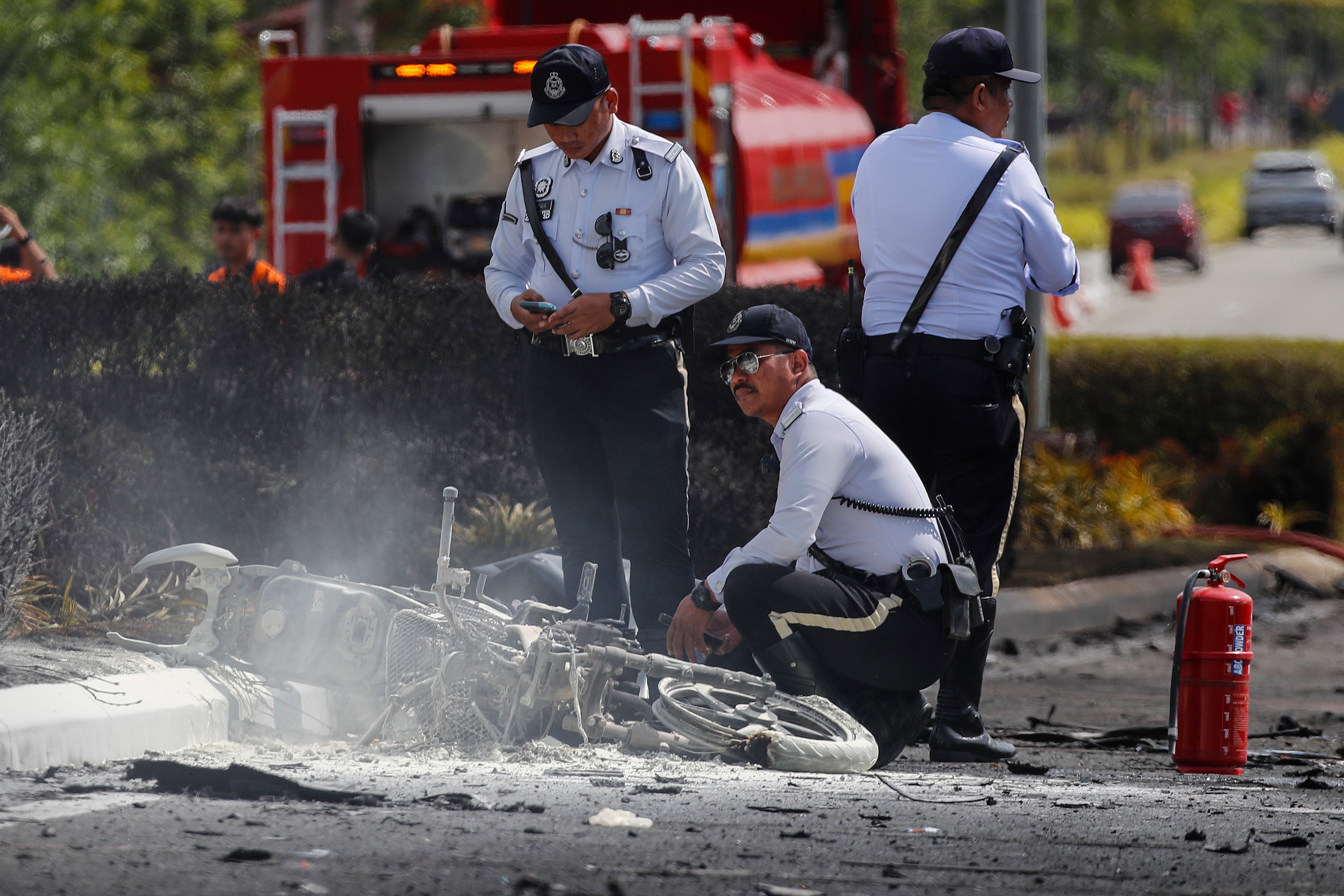 Officials inspect the site after an aircraft crashed into a motorway in Malaysia