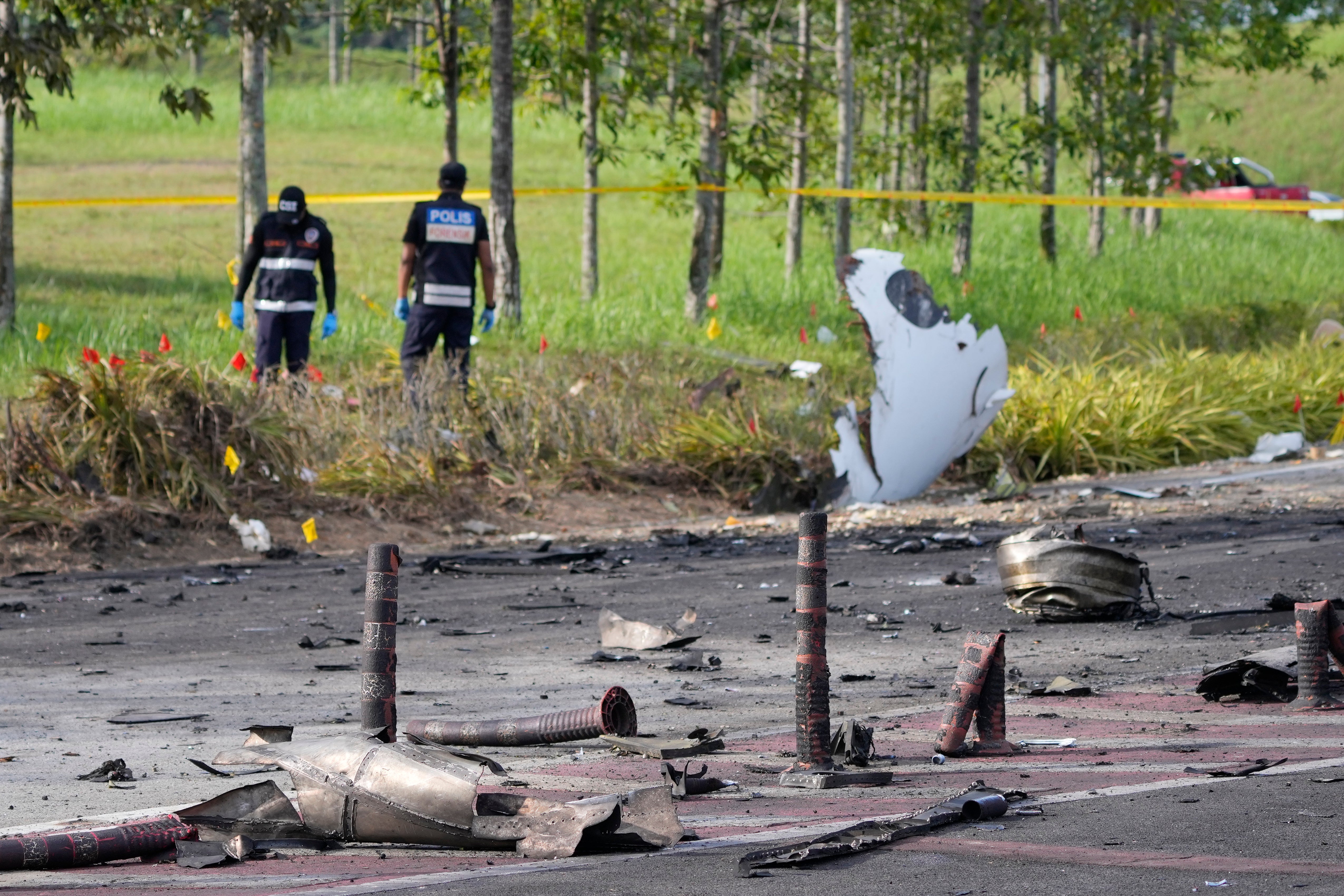 Members of the fire and rescue department inspect the crash site of a small plane in Shah Alam district