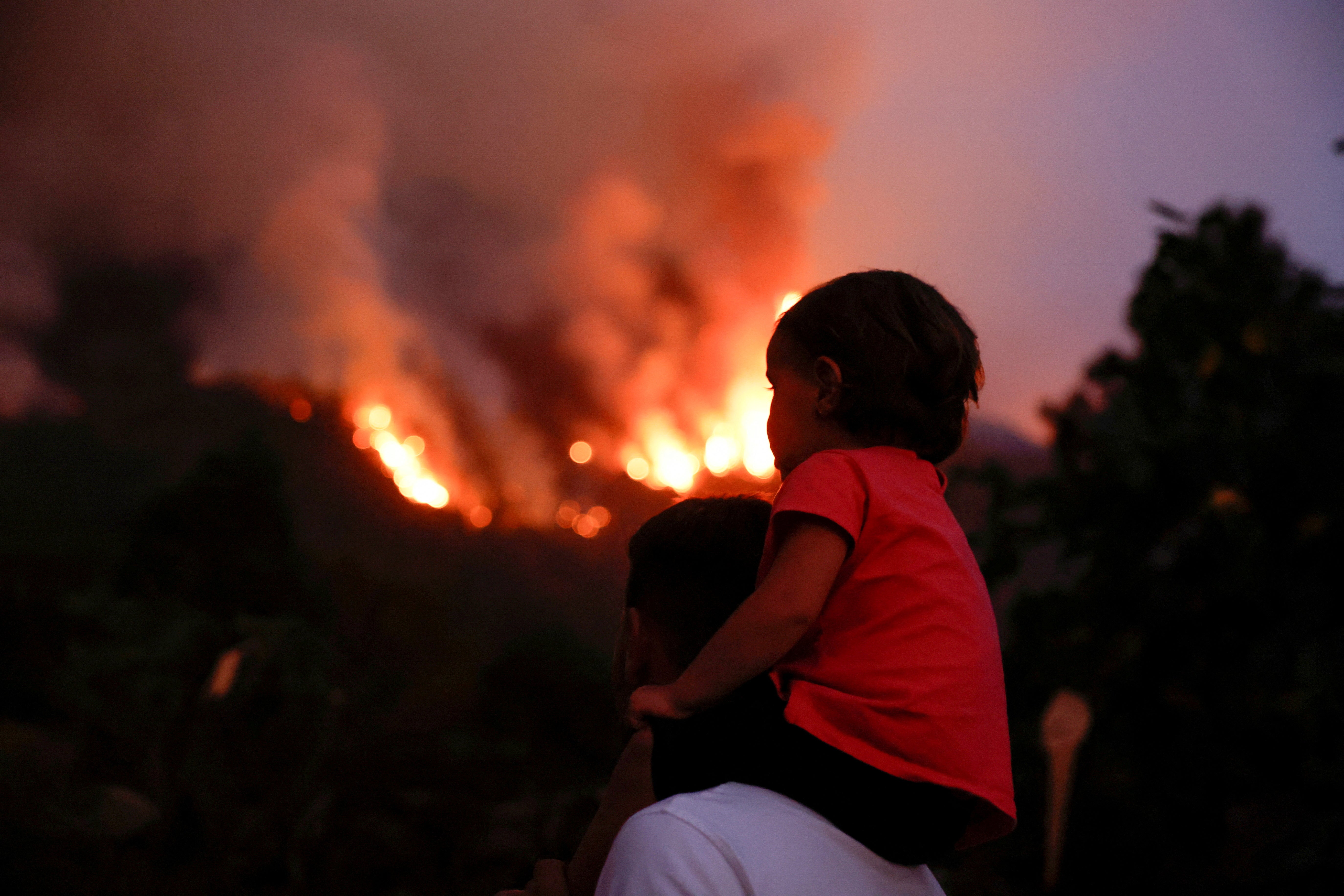 Residents of the town of Aguamansa watch the wildfires rage out of control on the island of Tenerife