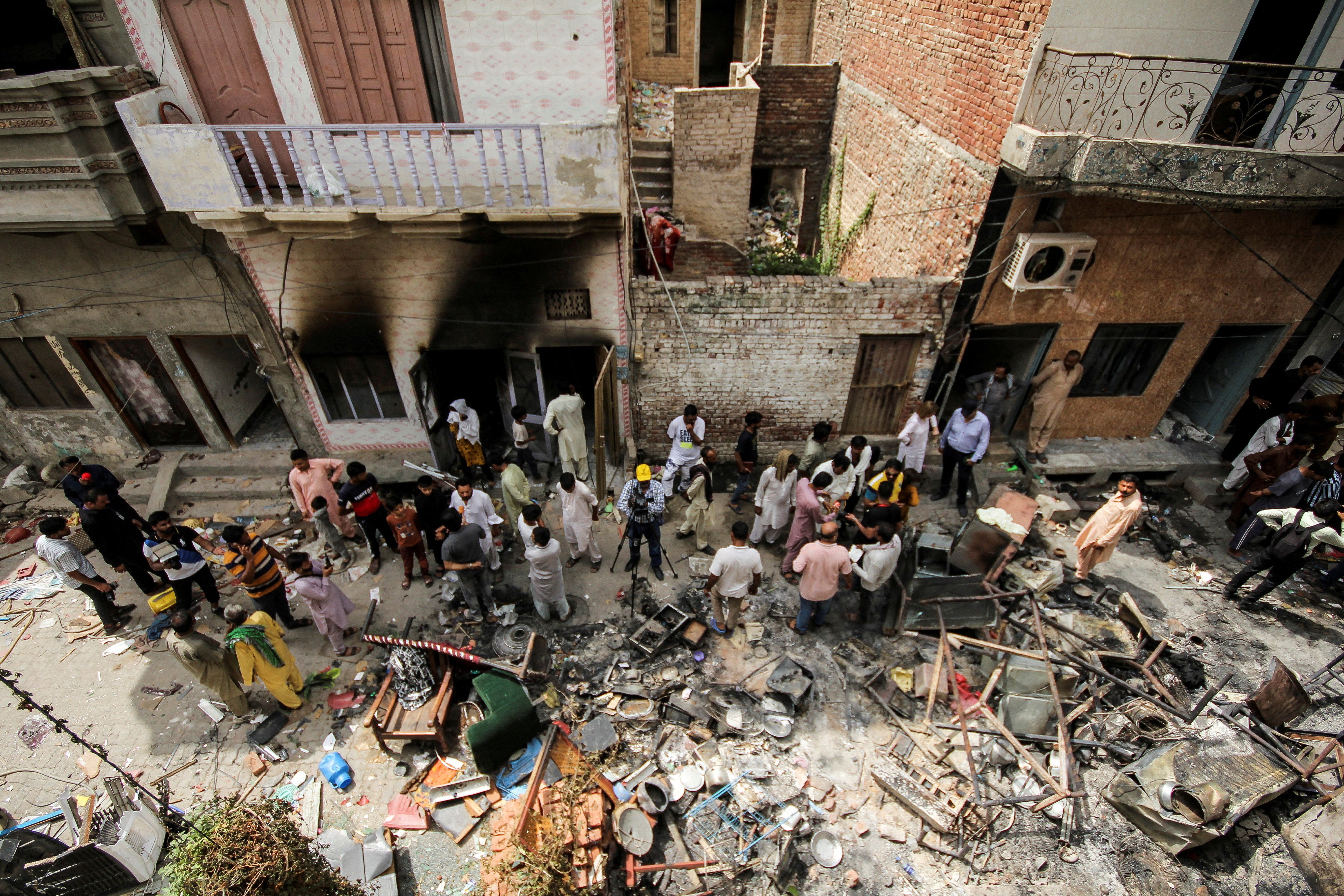 Onlookers and media representatives gather along a street in a Christian neighbourhood, a day after the church buildings and houses were vandalised by protesters in Jaranwala