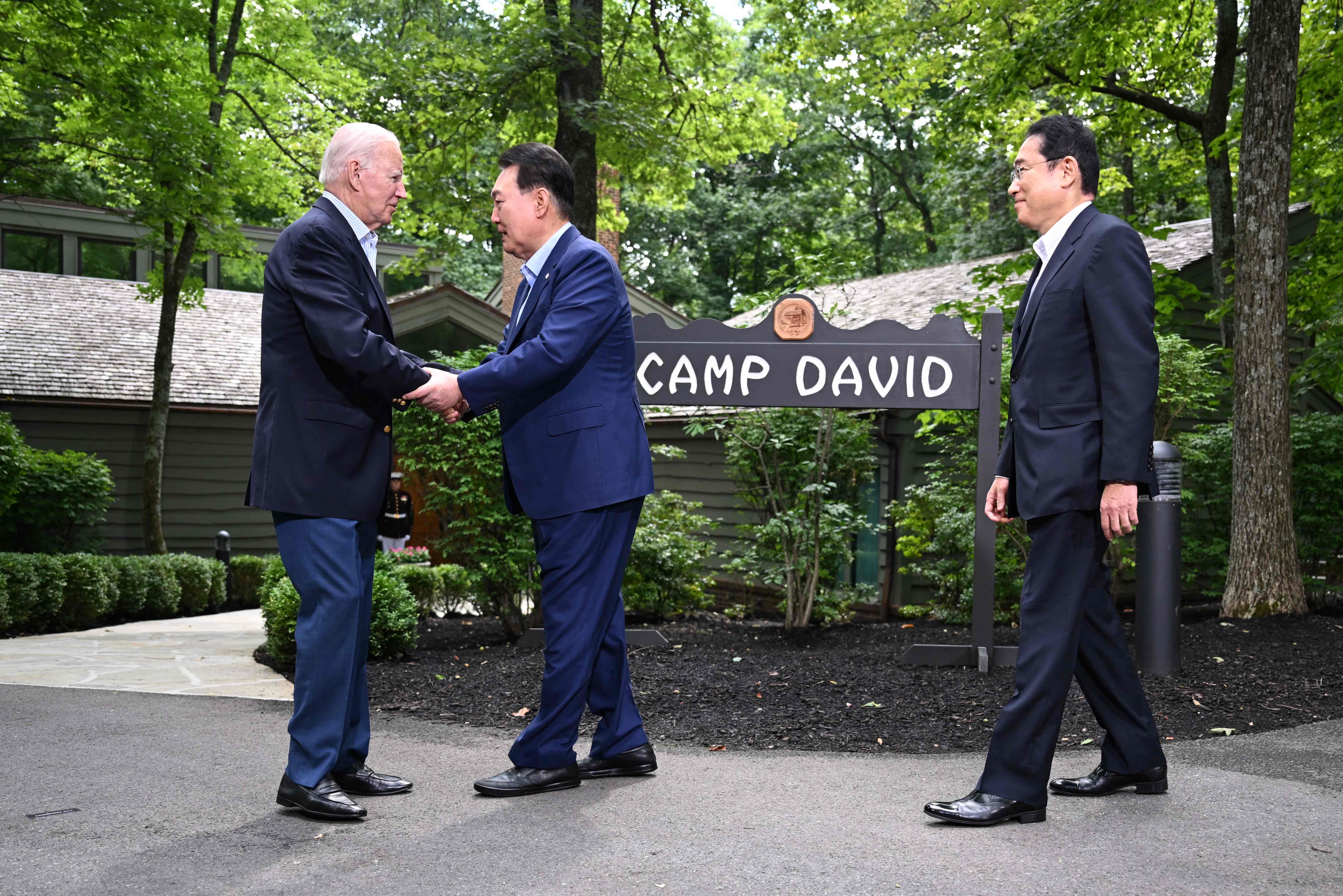 President Joe Biden (L), greets Japanese Prime Minister Fumio Kishida (R), and South Korean President Yoon Suk Yeol (C) during the Camp David Trilateral Summit