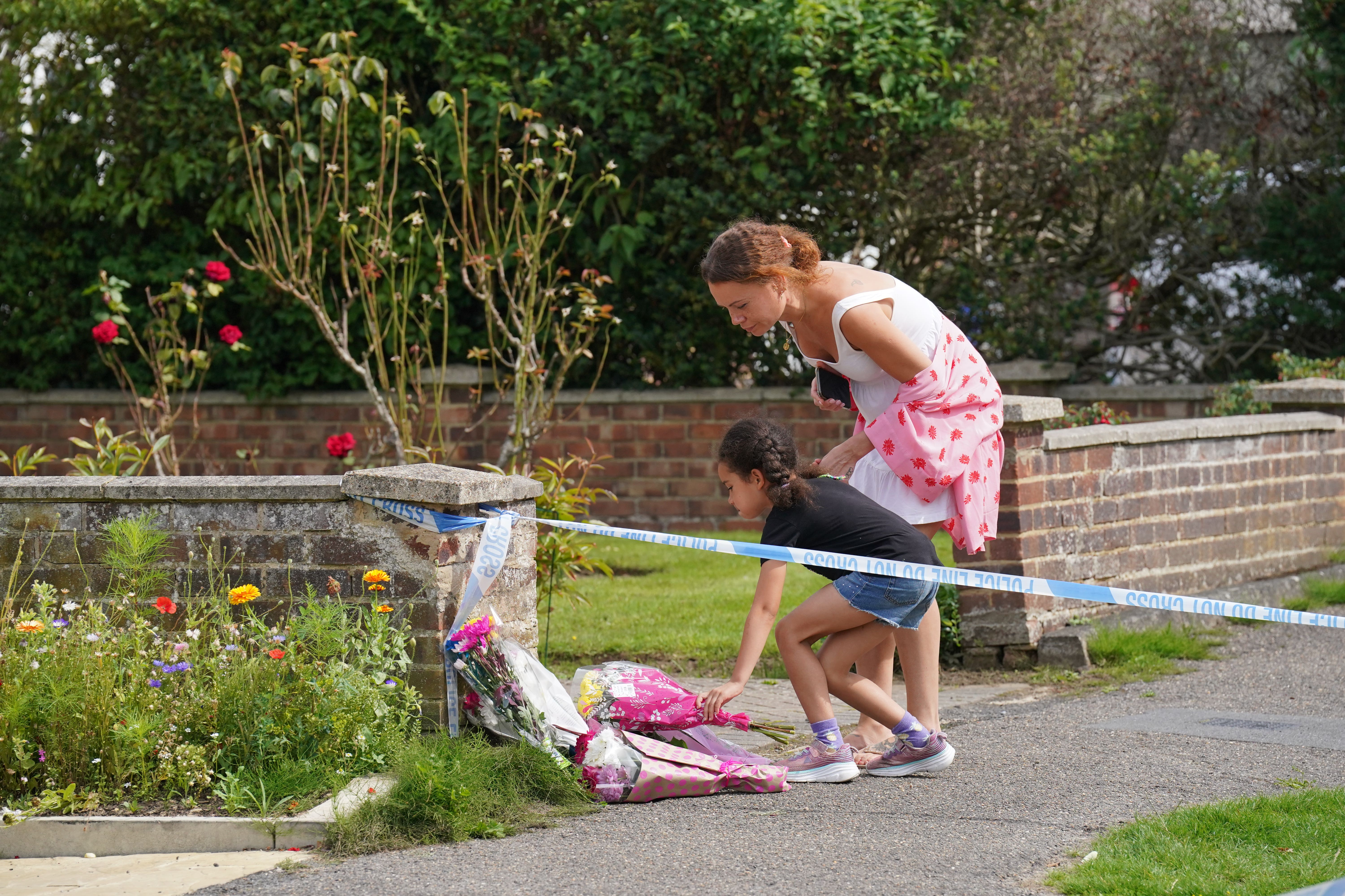 People lay flowers for Sara outside her home in Woking, Surrey