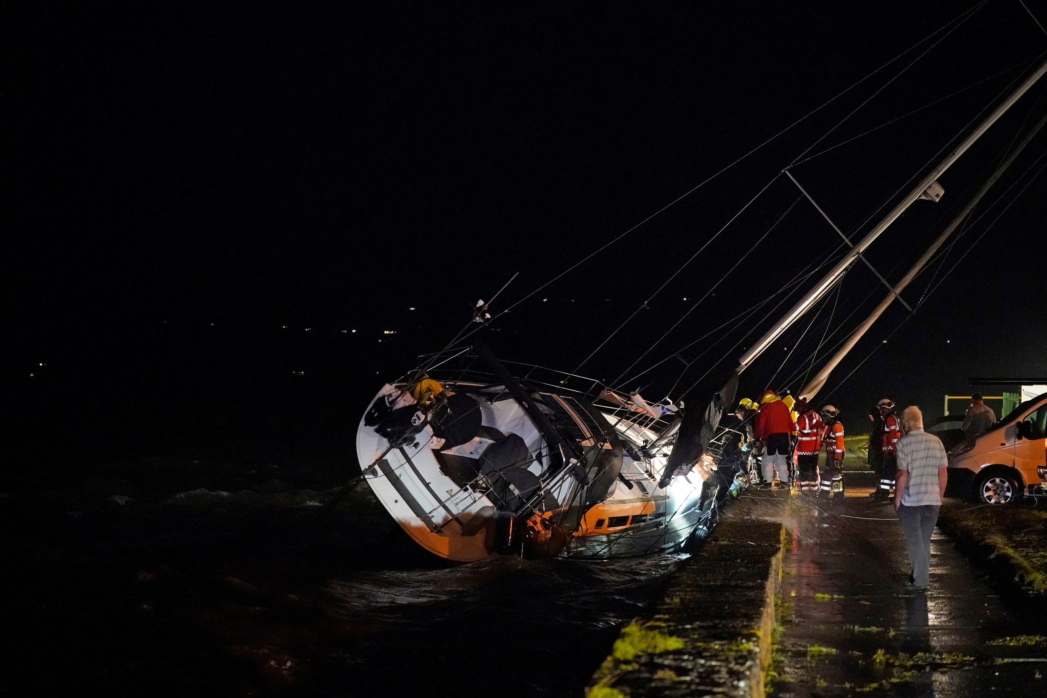 Members of the Coast Guard inspect the damage to a boat after it broke free from its berth and crashed into the harbour during Storm Betty in Dungarvan, County Waterford