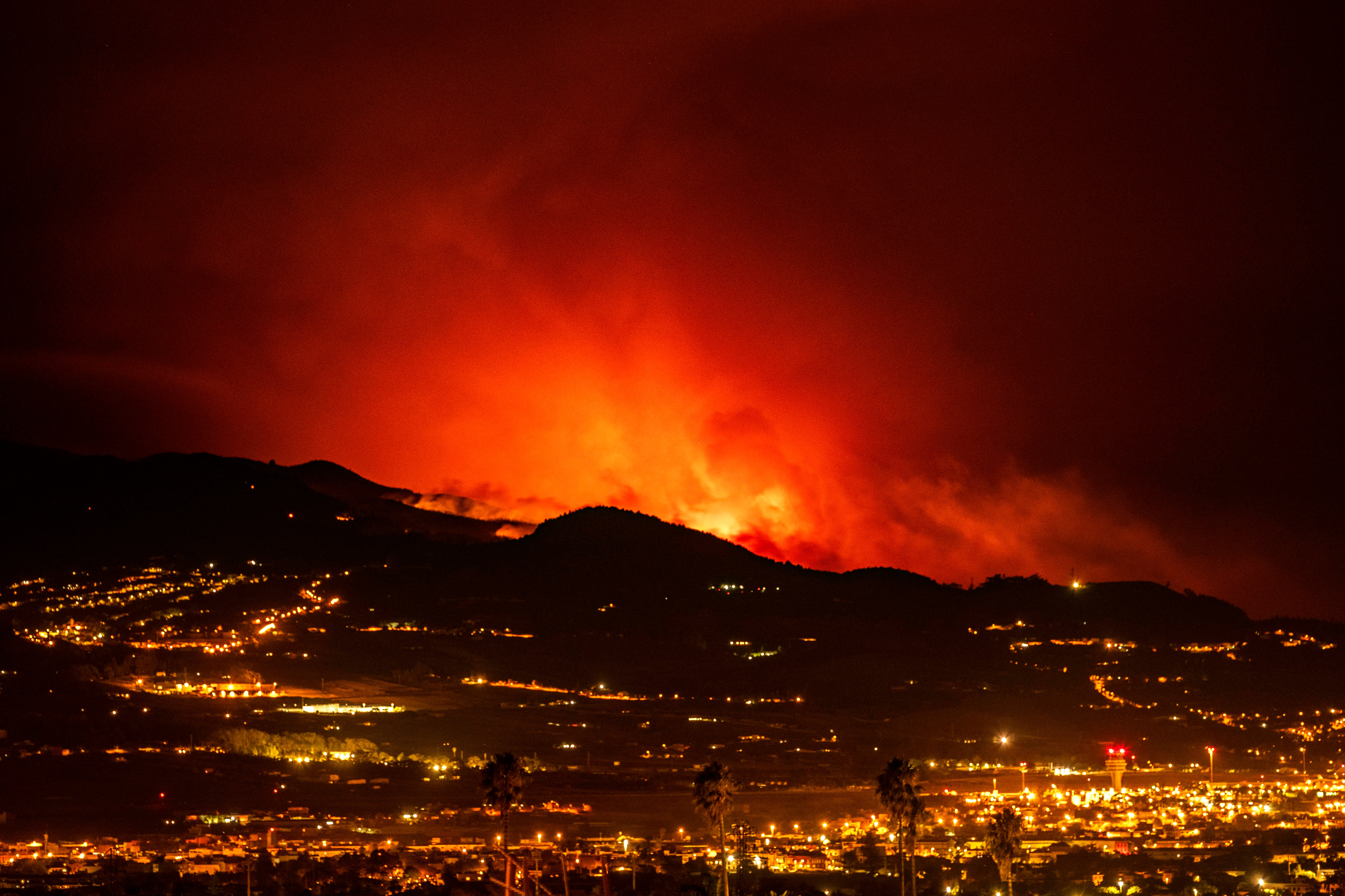 Flares are seen on the horizon as the fire advances through the forest toward the town of La Laguna and Los Rodeos airport in Tenerife on Saturday