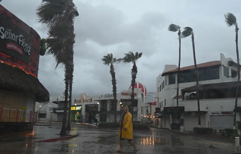 A man walks along a street in Cabo San Lucas, Baja California State, Mexico, as rain and gusts of wind of Hurricane Hilary reach the area