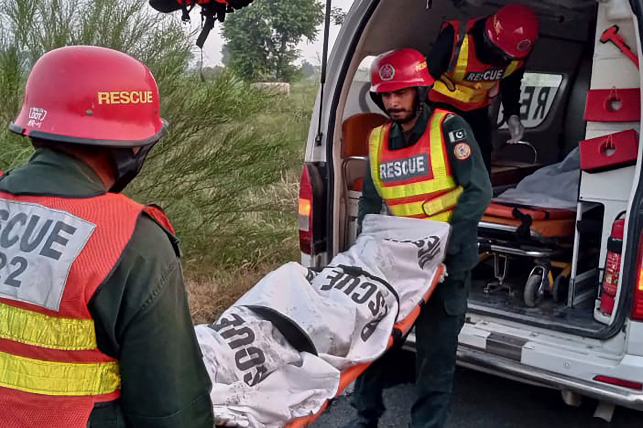 prescue workers load a body into an ambulance after recovering from a burnt bus at the accident site on a highway/p