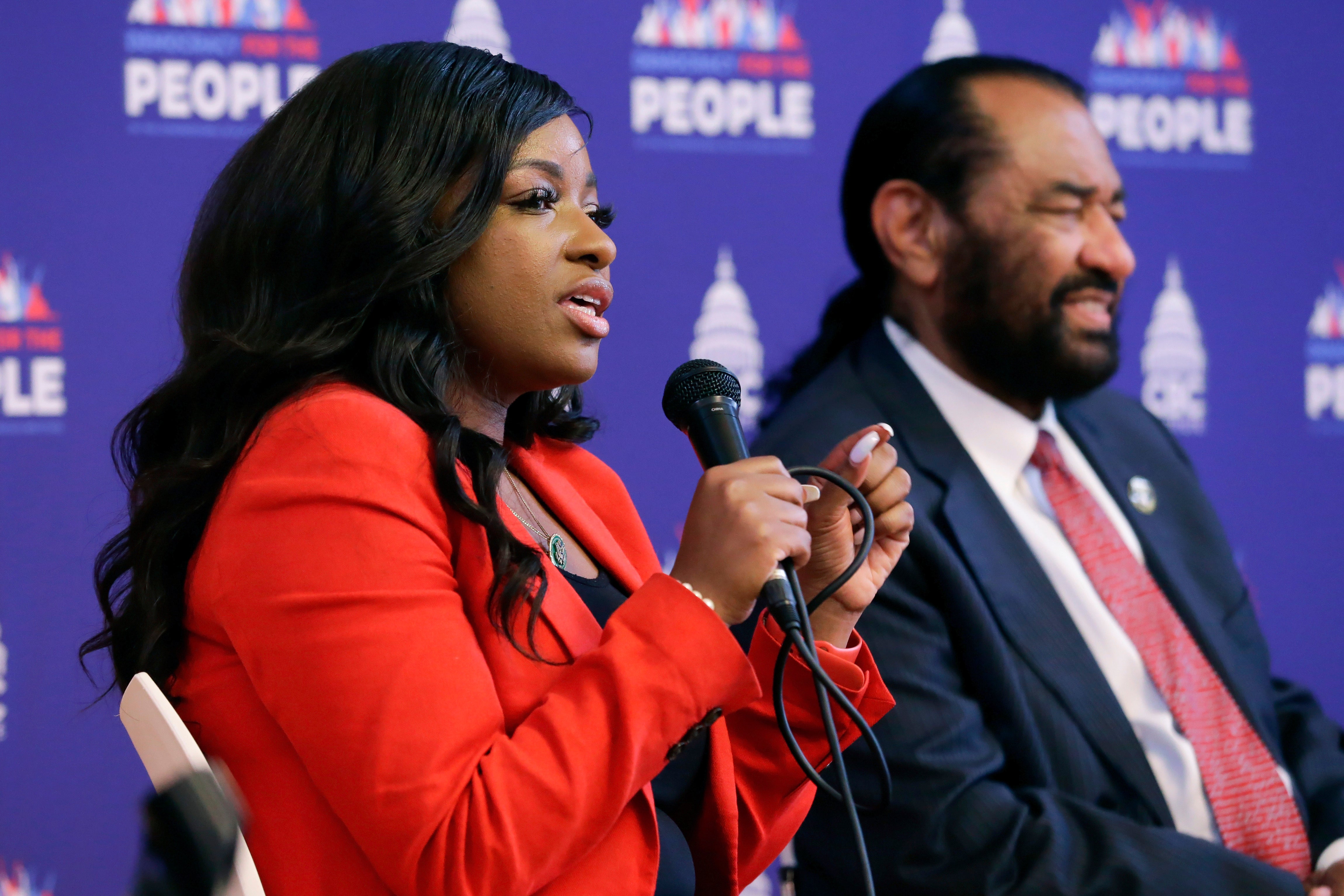 Rep Jasmine Crockett, D-Texas, left, speaks as Rep. Al Green, D-Texas, listens during a stop of the "Democracy for the People" tour, a race and democracy summit sponsored by the Congressional Black Caucus, Wednesday, July 28, 2023, in Houston.