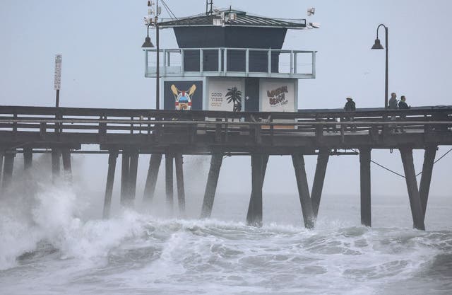 <p>People stand on a pier over the Pacific Ocean with Tropical Storm Hilary approaching in San Diego County on August 20, 2023 in Imperial Beach, California</p>