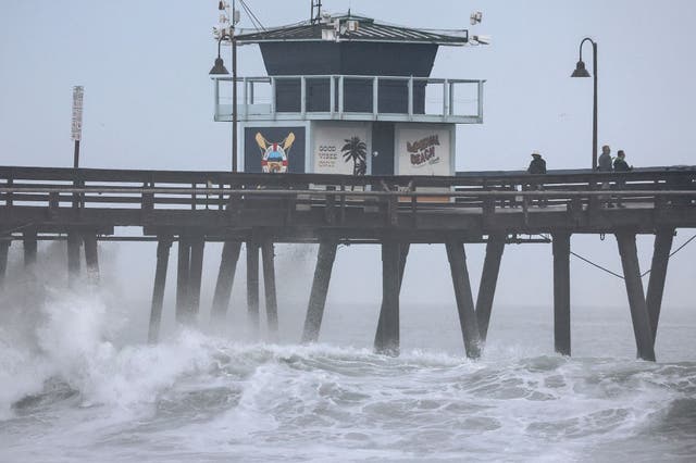 <p>People stand on a pier over the Pacific Ocean with Tropical Storm Hilary approaching in San Diego County on August 20, 2023 in Imperial Beach, California</p>