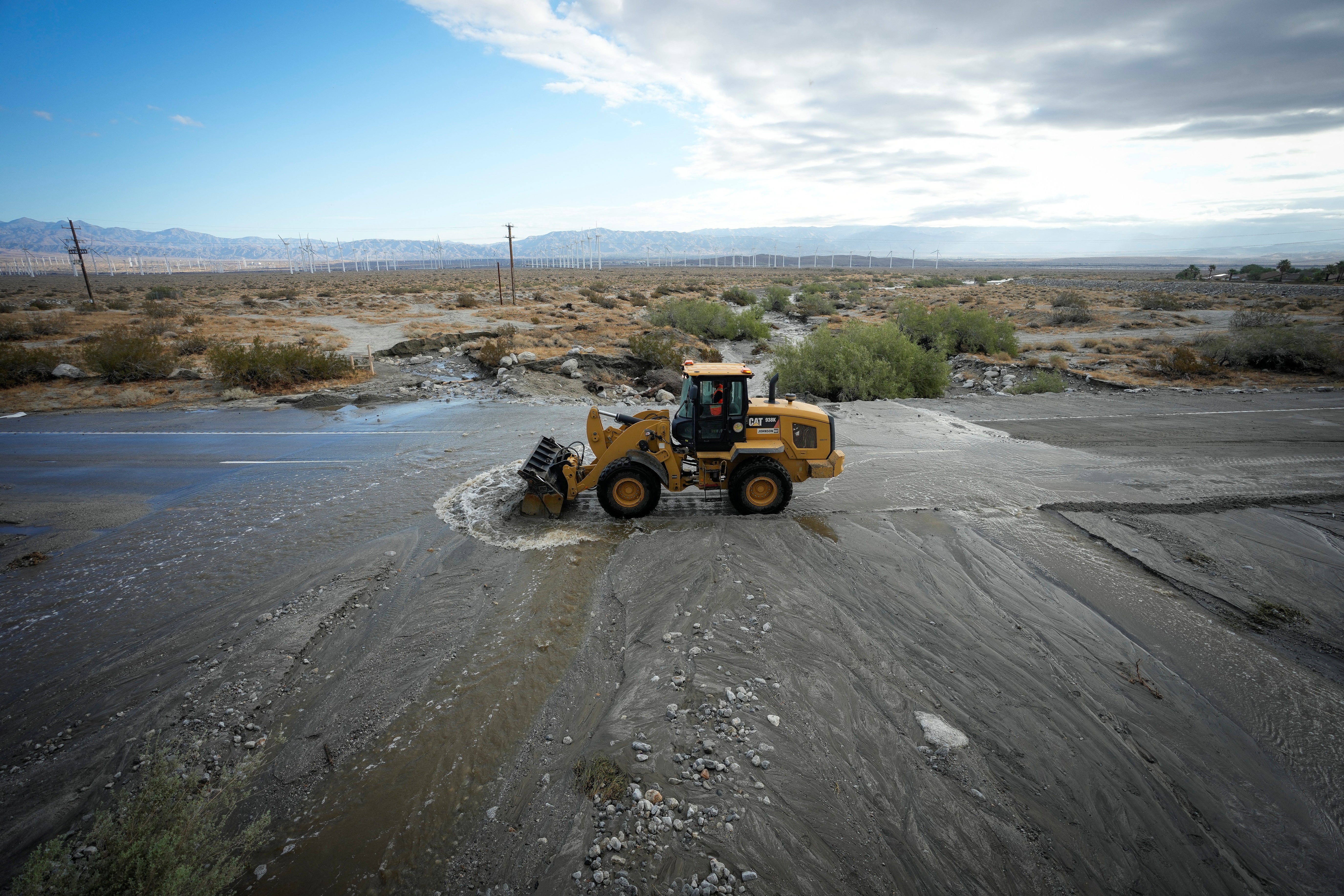 A road crew works to clear debris from California State Highway 111, a major road leading in and out of Palm Springs, covered with moving water the morning after Tropical Storm Hilary passed Palm Springs, California, U.S., August 21, 2023