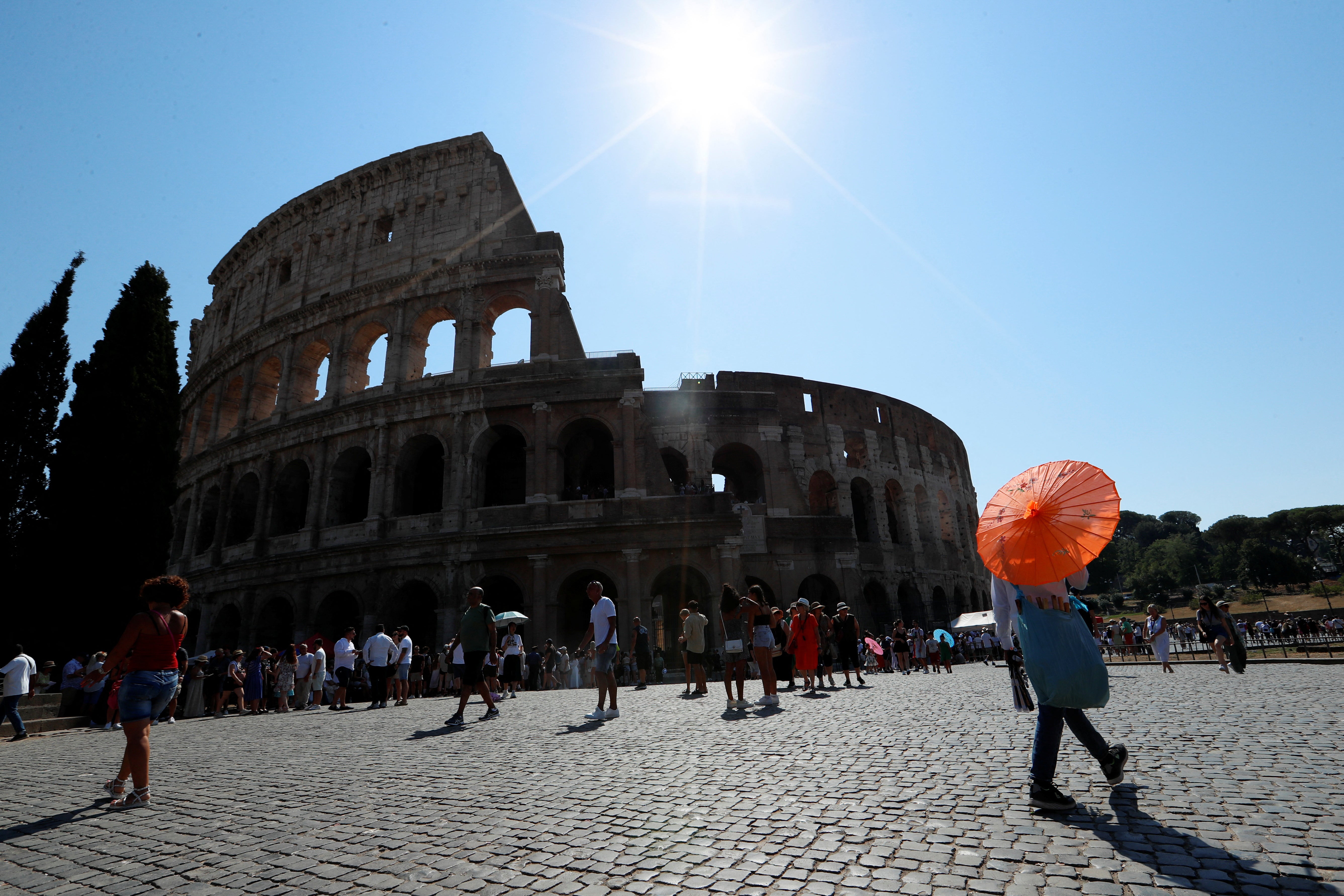 People walk near the Colosseum during a new heatwave as temperatures are expected to reach 40 degrees Celsius in some cities
