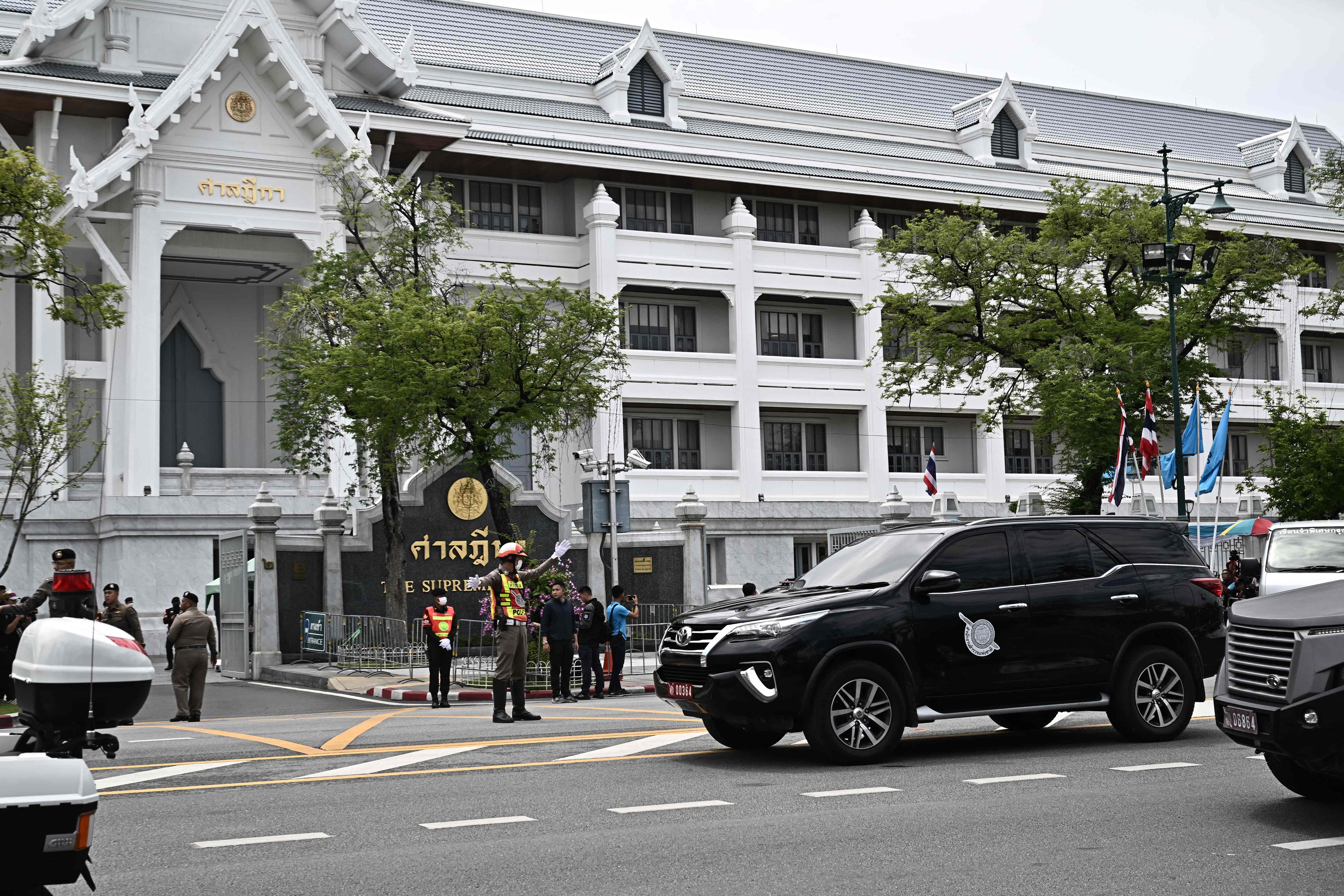 A police car (right) believed to be carrying Shinawatra leaves Thailand’s Supreme Court