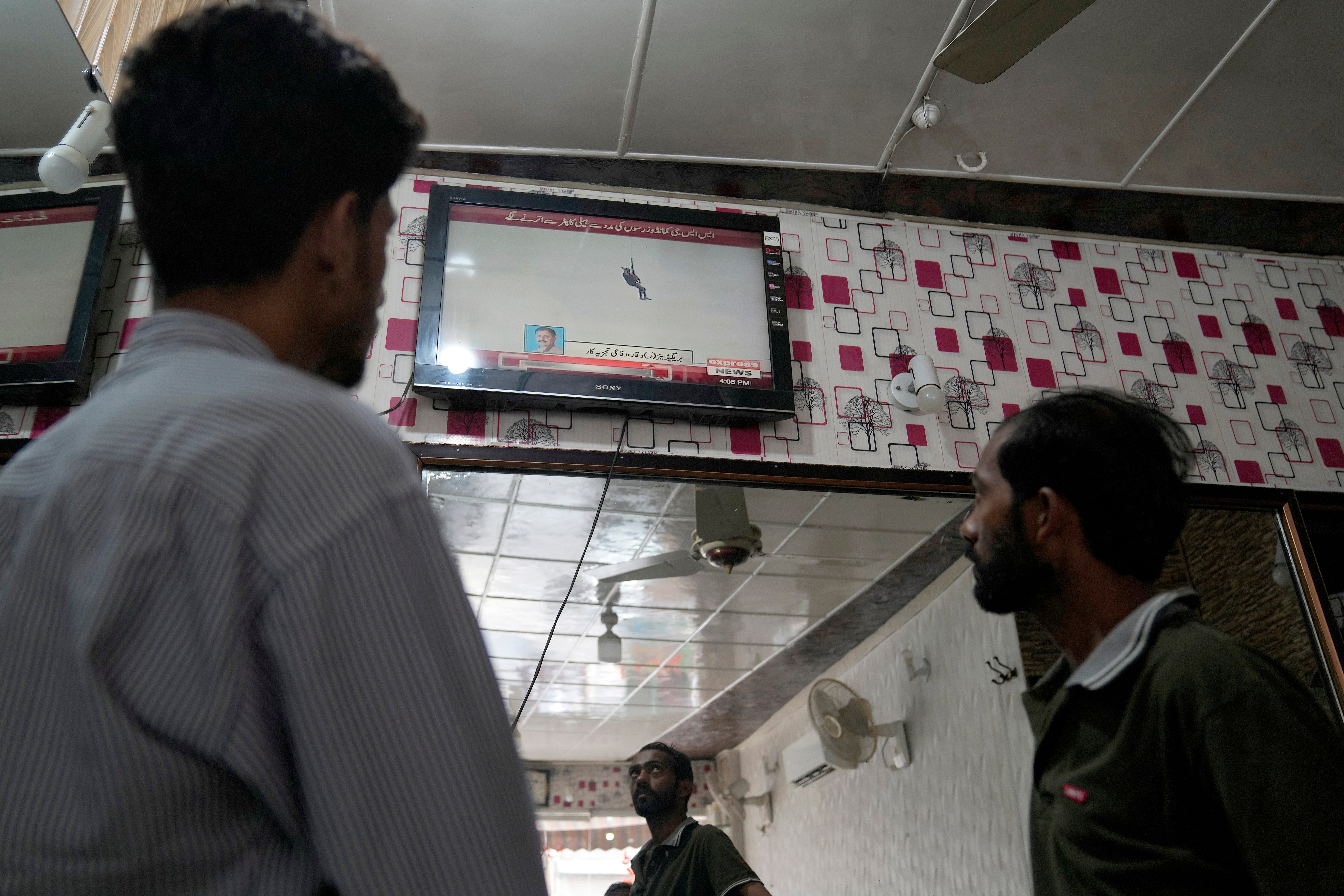 People were watching a news channel broadcasting information about the rescue, at a barber shop in Lahore