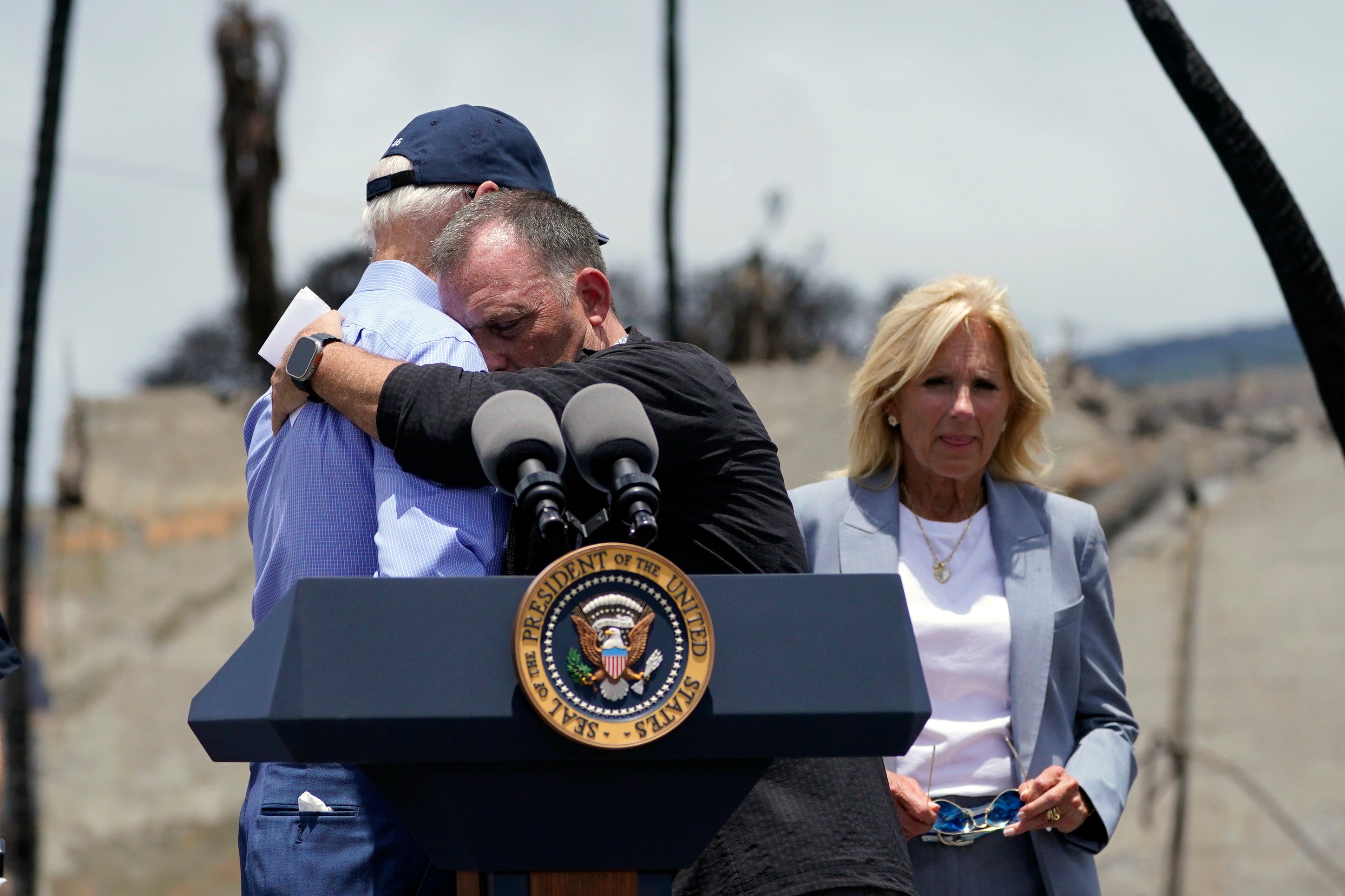 Hawaii Gov. Josh Green hugs President Joe Biden before he speaks after touring areas devastated by the Maui wildfires