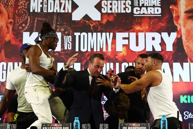 <p>KSI, left, is held back as Tommy Fury tries to lay hands on him</p>