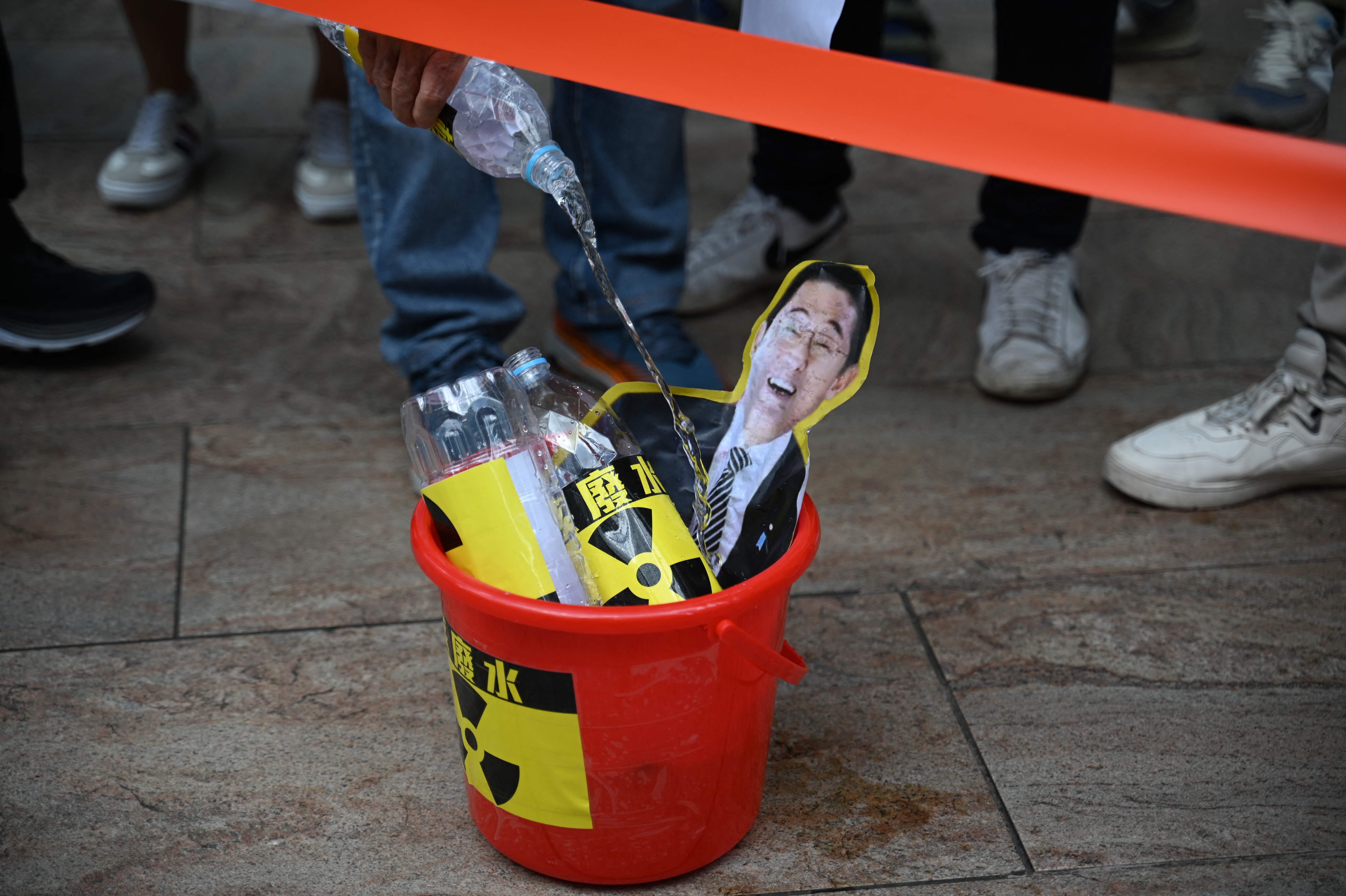 Hong Kong fishermen pour water on a depiction of Japan's Prime Minister Fumio Kishida at a protest outside the Japanese consulate in Hong Kong