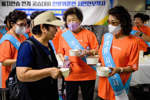 A civilian is offered snacks and bottled water during a civil defence drill against possible artillery attacks by North Korea, in a subway station in Seoul on 23 August 2023