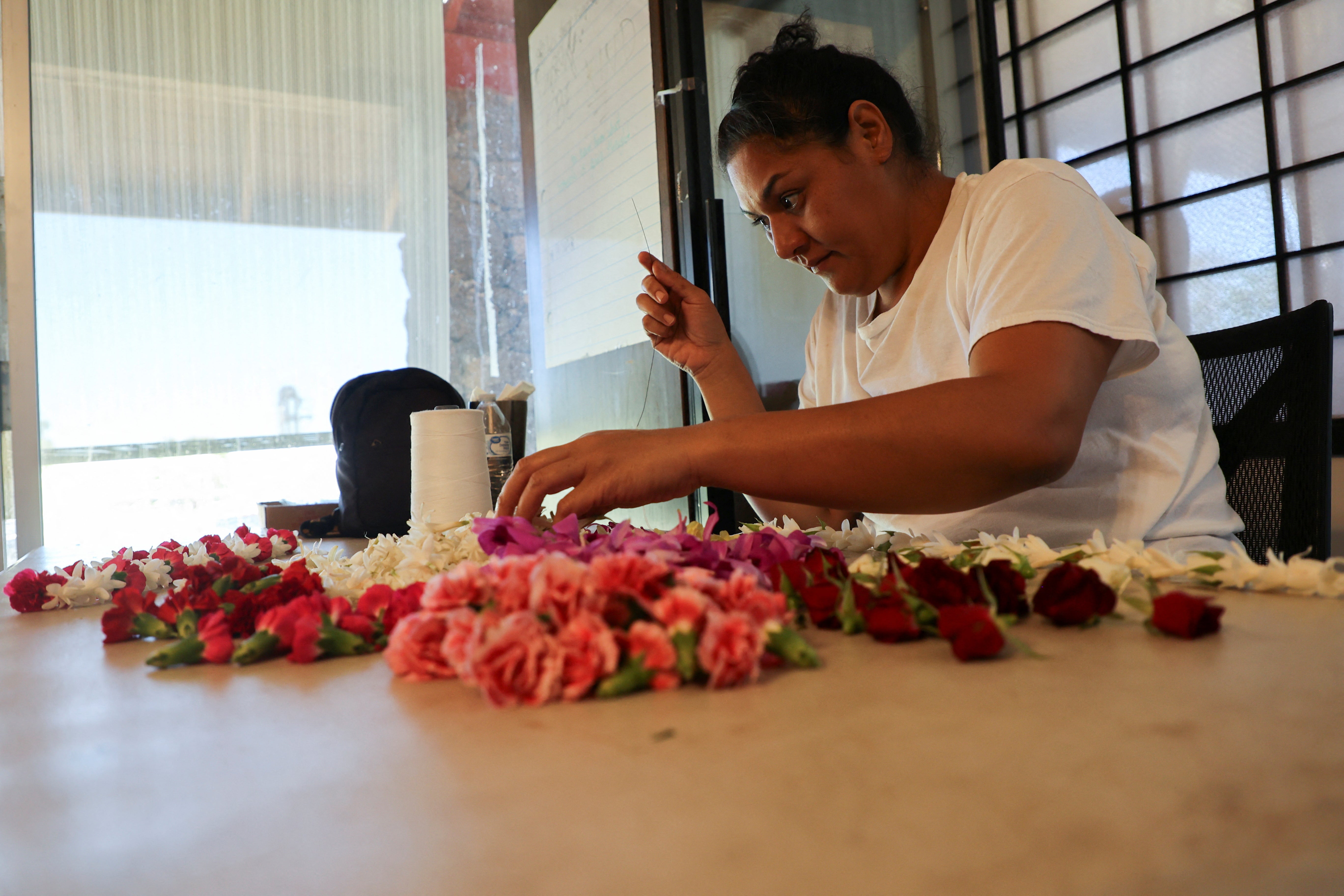 A worker at Maui Floral makes a lei, a traditional Hawaiian symbol that has taken on added significance in times of grief for the community of Lahaina in Makawao, Hawaii,