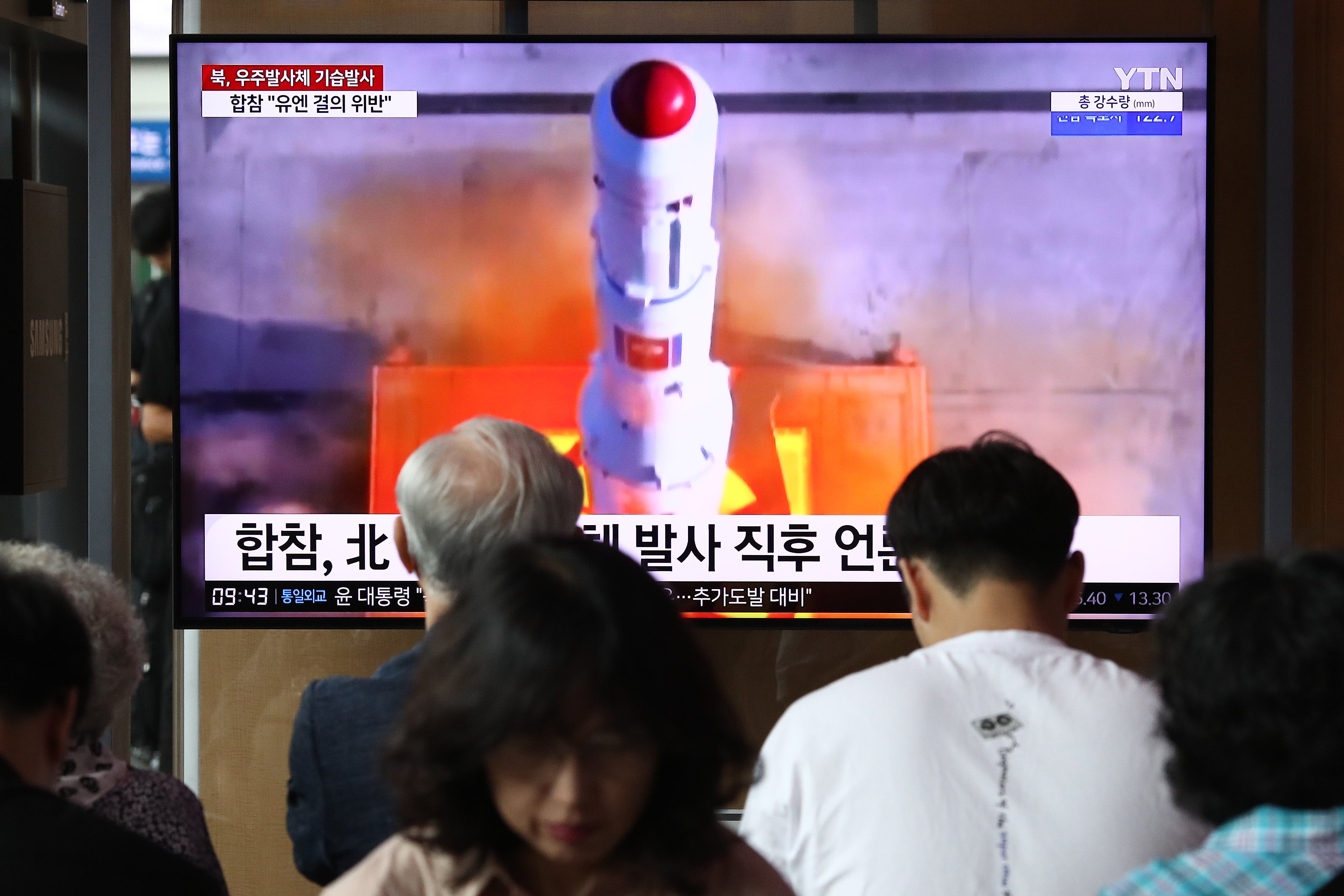 People watch a television broadcast showing a file image of a North Korean rocket launch at the Seoul Railway Station on 24 August