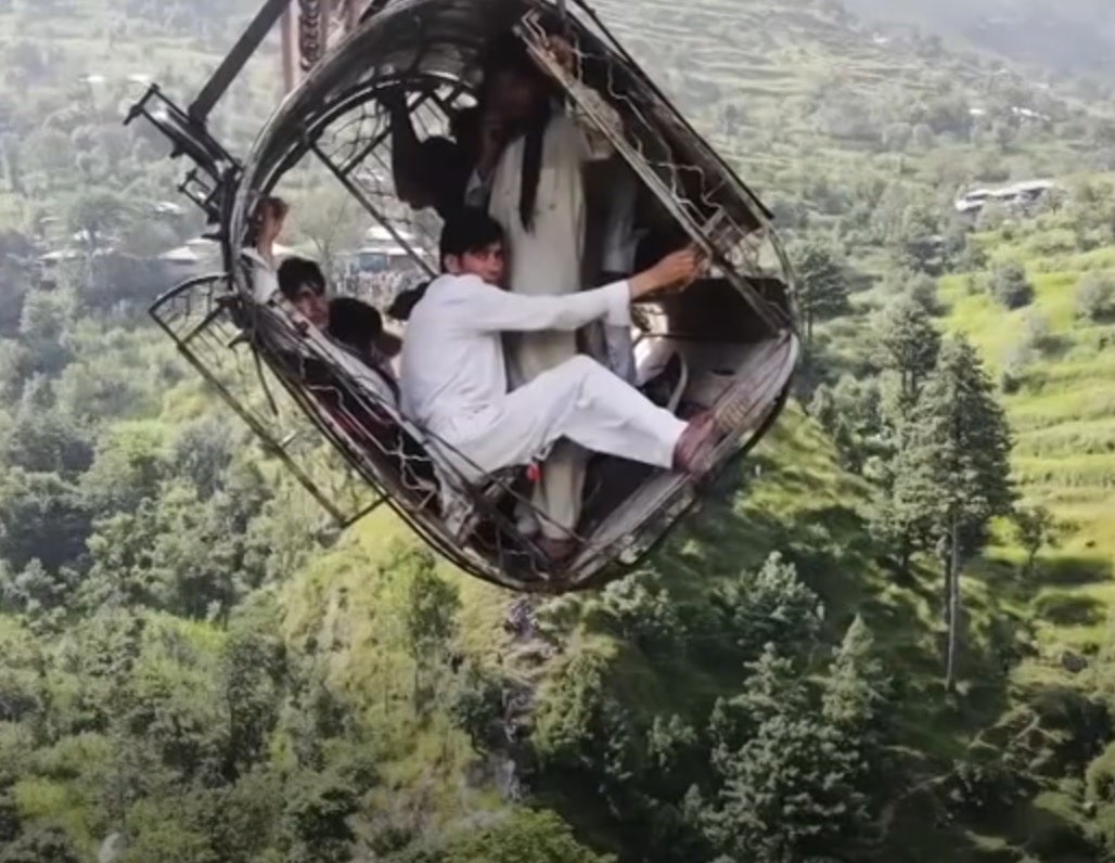 <p>Survivors seen in drone footage clinging on for dear life to tiny cable car that was left dangling above 900ft in a remote area in Pakistan</p>