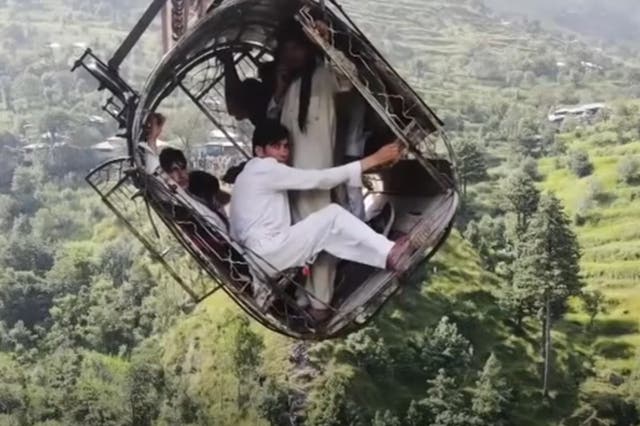 <p>Survivors seen in drone footage clinging on for dear life to tiny cable car that was left dangling above 900ft in a remote area in Pakistan</p>