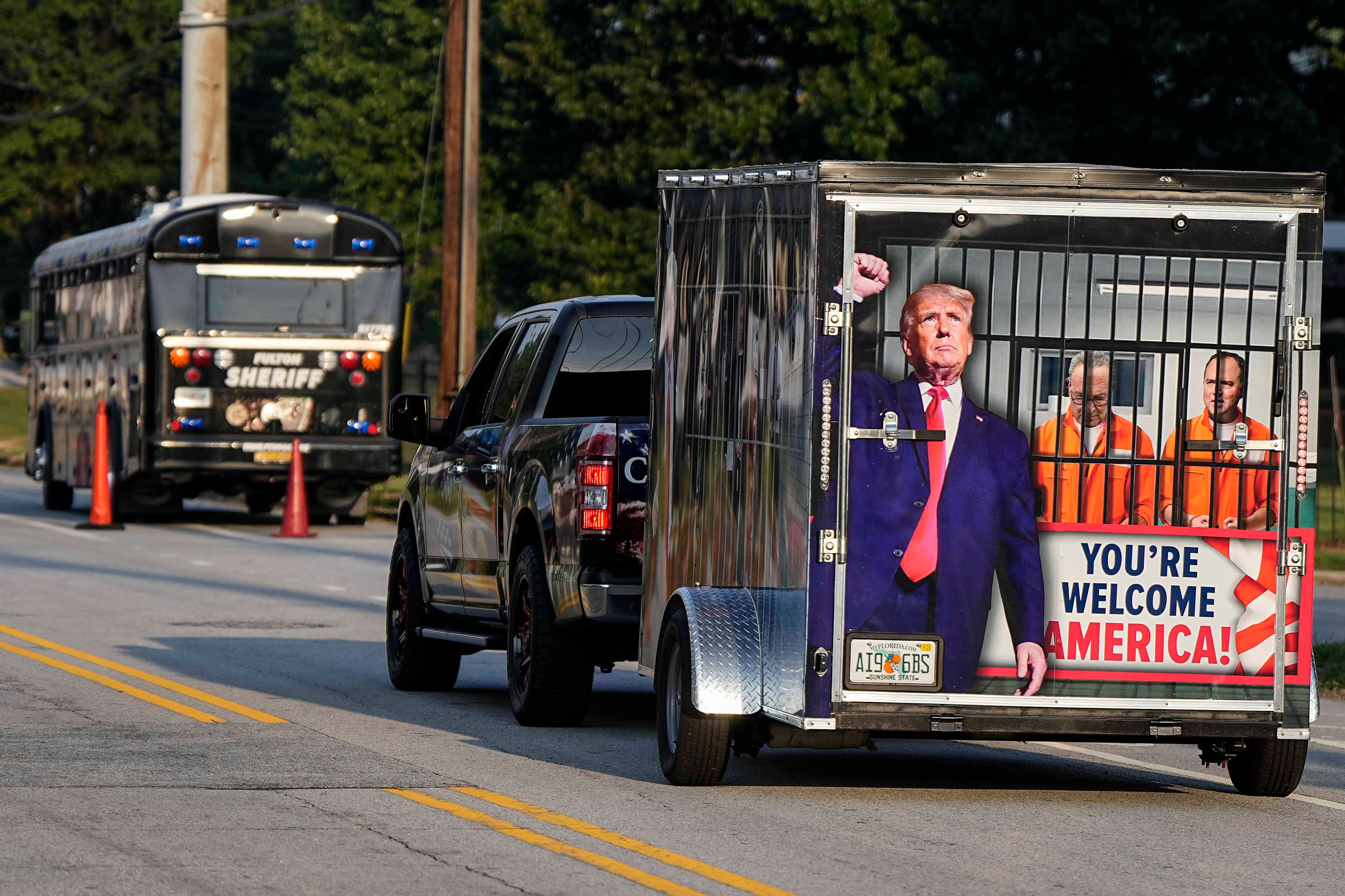 A Trump supporter drives a trailer depicting adversaries of the former president behind bars