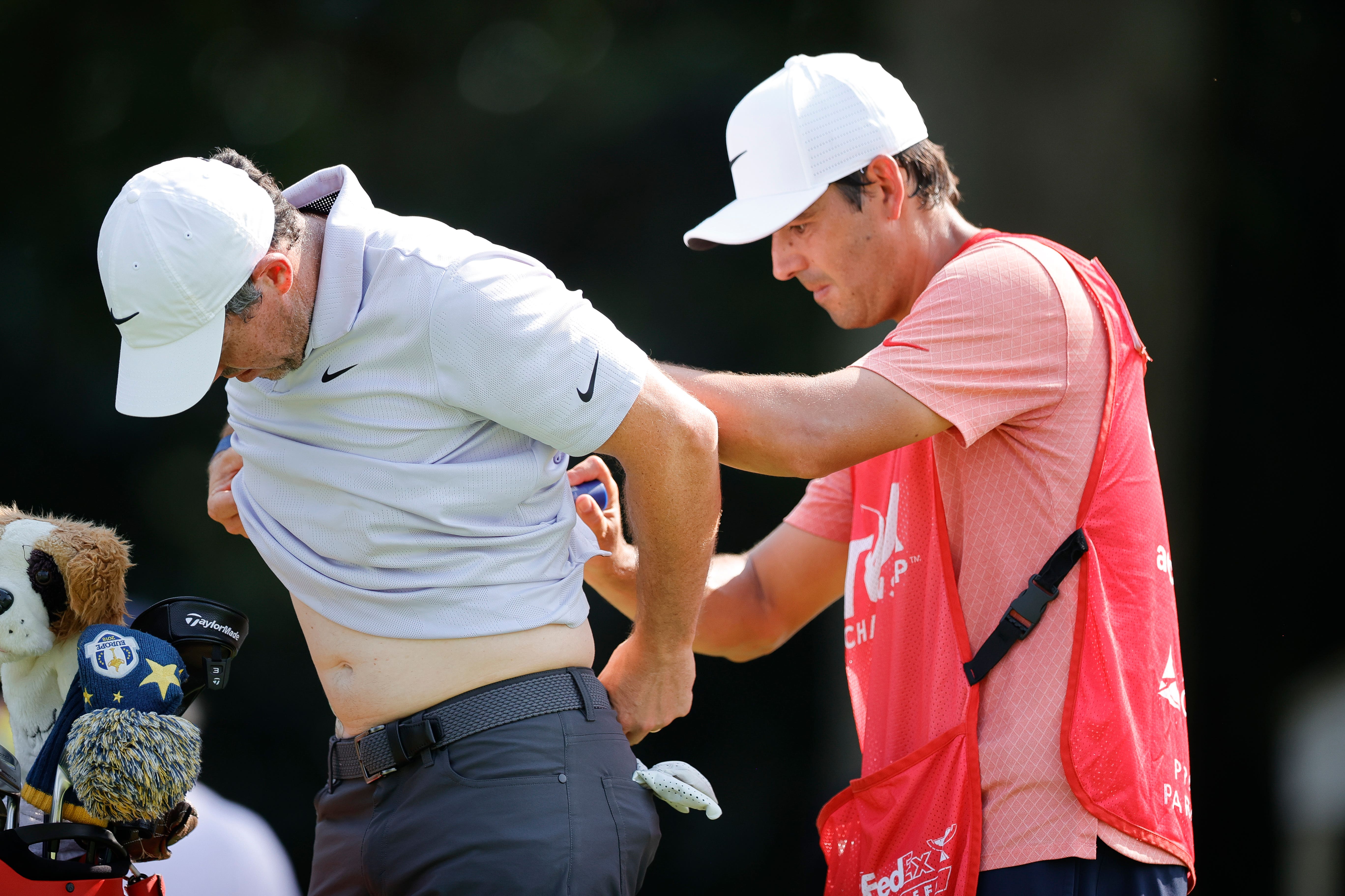 Rory McIlroy, left, has pain-relieving balm applied to his back by his caddie Harry Diamond during the first round of the Tour Championship golf tournament in Atlanta (Alex Slitz/ AP)