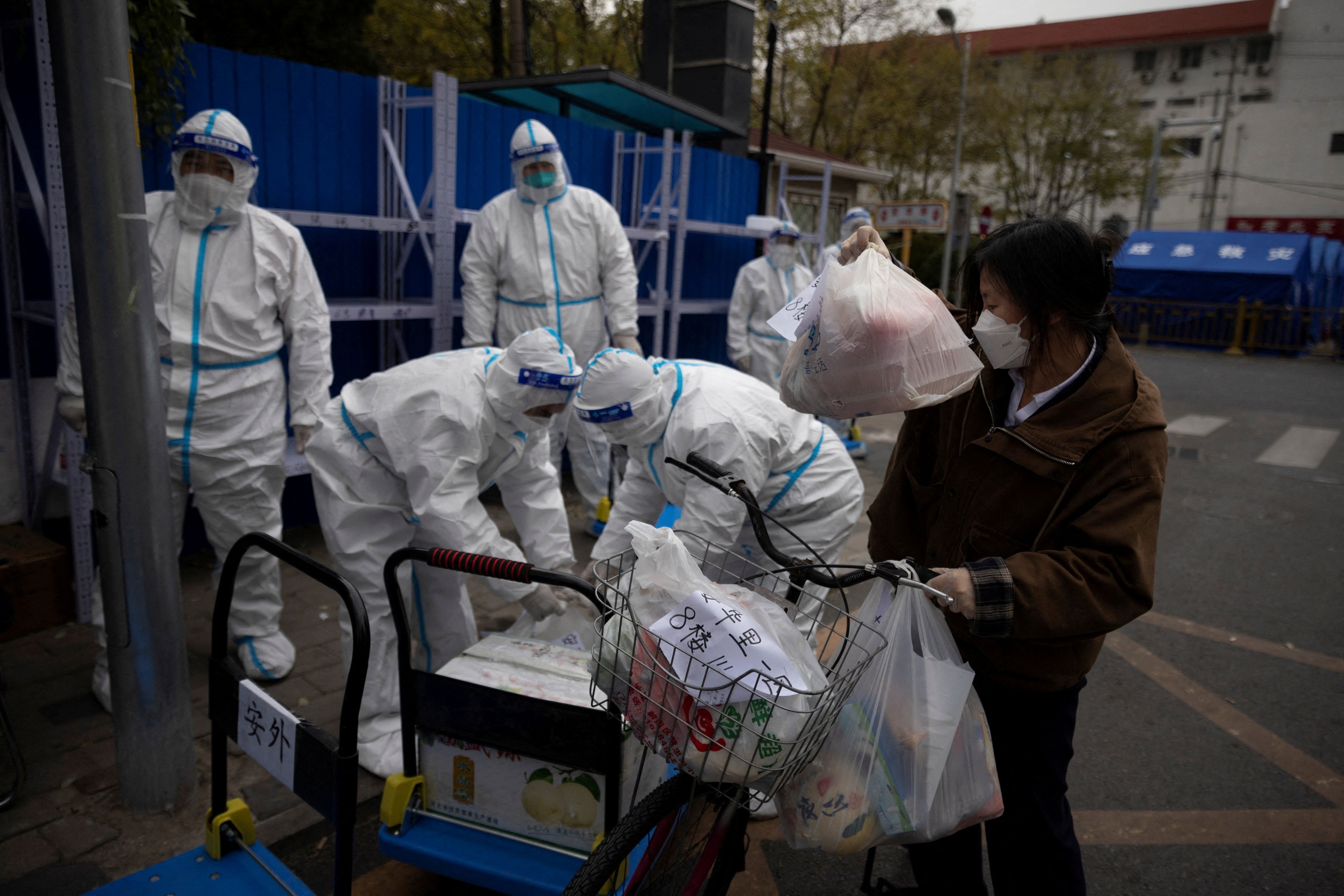 <p>File: A woman delivers food to a residential compound that is under lockdown as outbreaks of coronavirus disease</p>