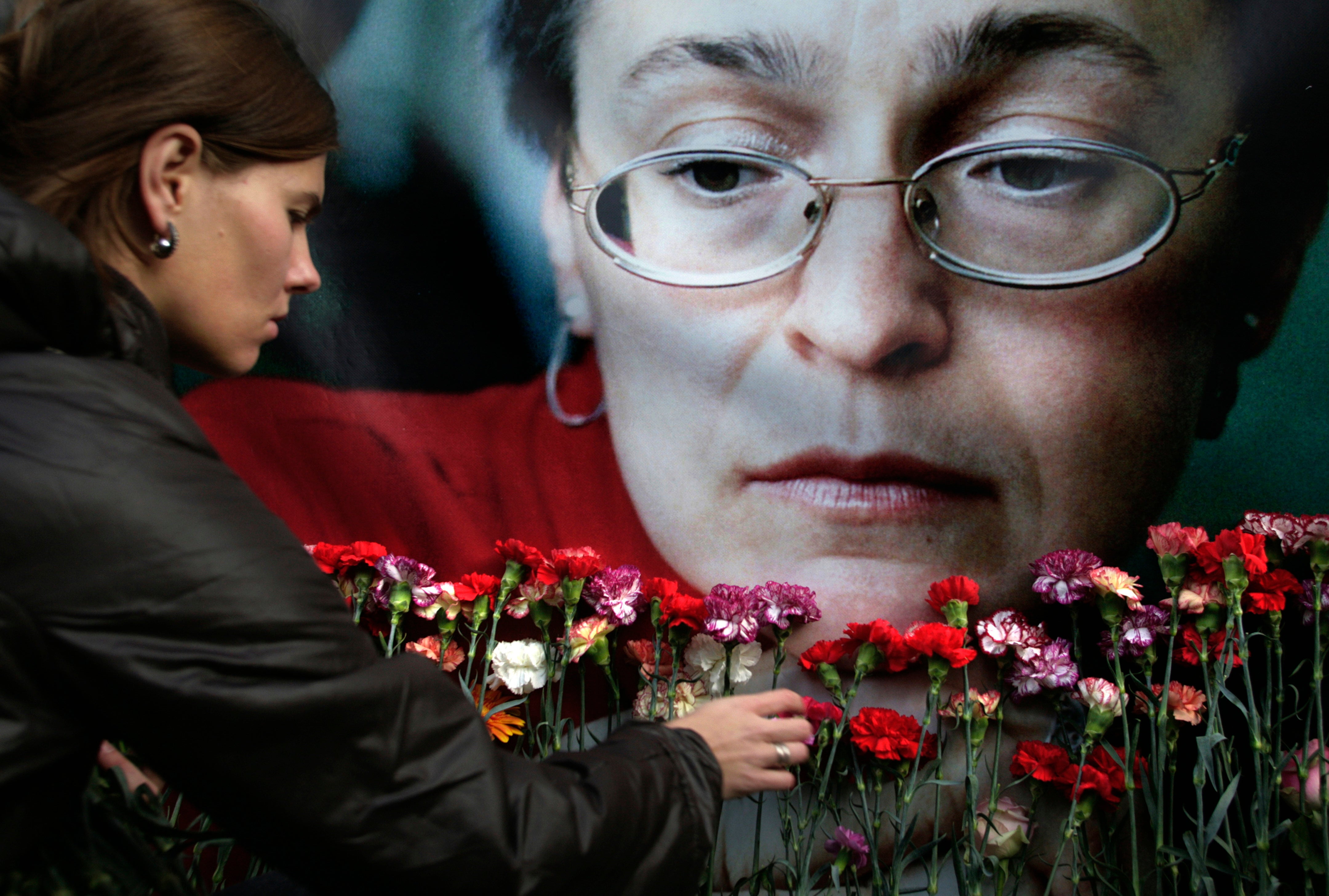 A woman places flowers before a portrait of murdered journalist Anna Politkovskaya