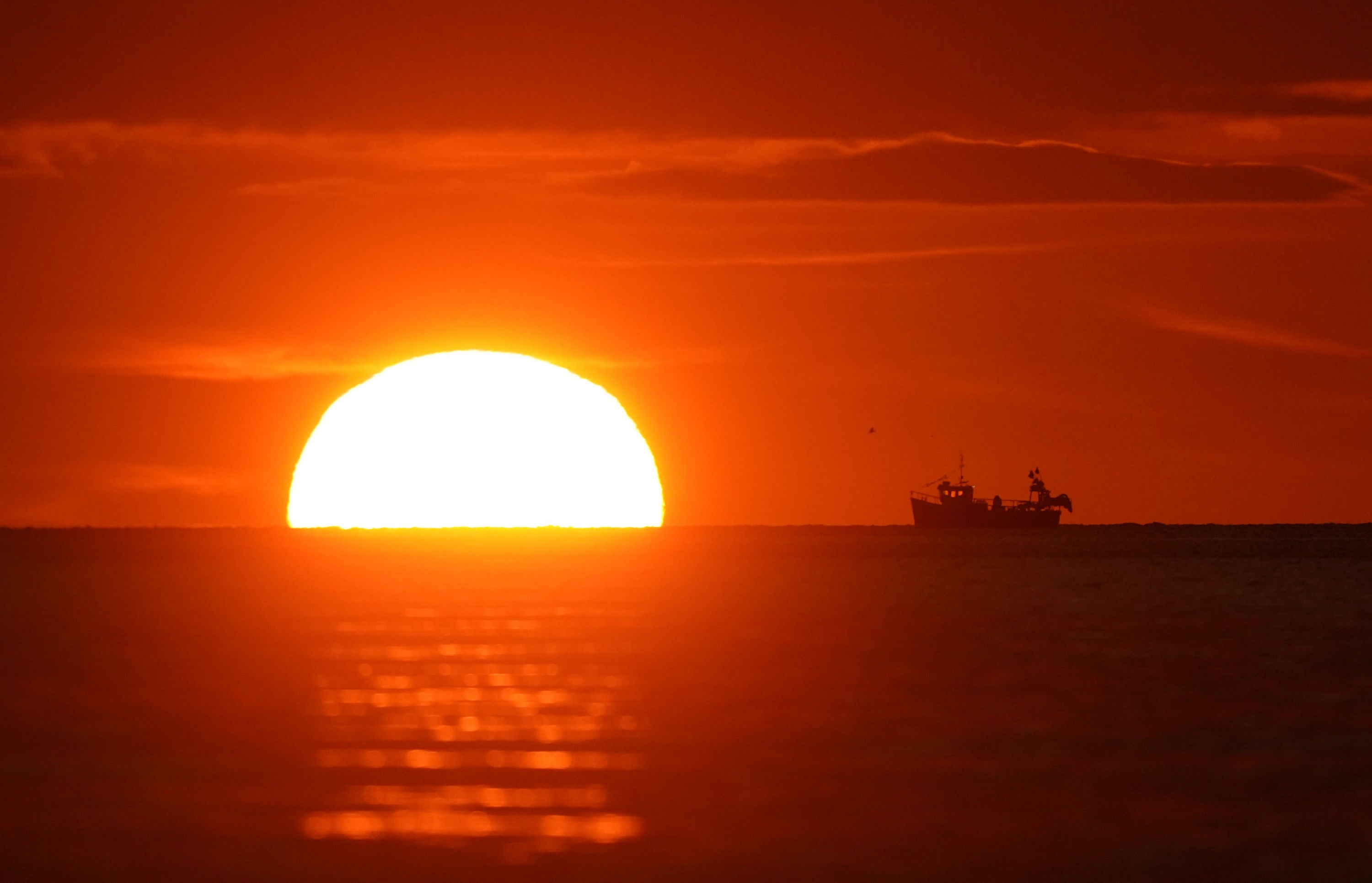 A fishing boat collects its pots during sunrise at Cullercoats Bay, North Tyneside
