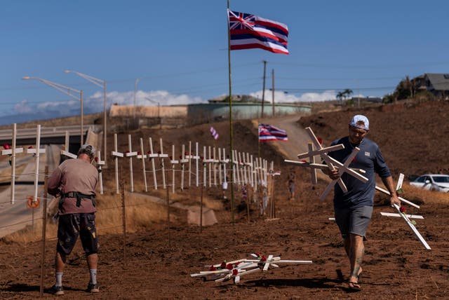 <p>Ethan Meyers, right, carries crosses to put up to honor the victims killed in a recent wildfire in Lahaina, Hawaii, Tuesday, Aug. 22</p>