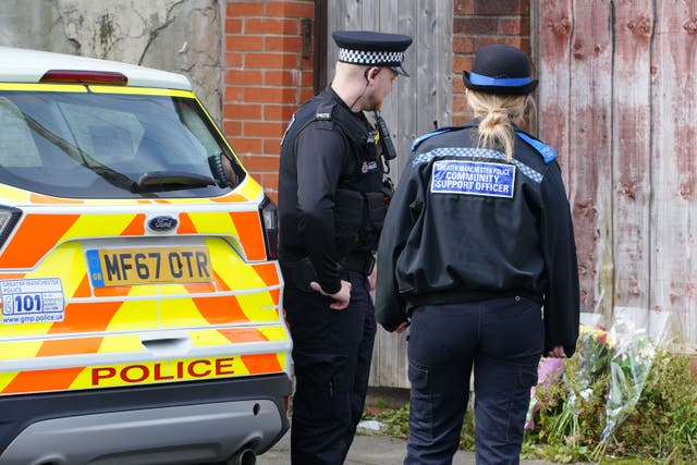 Police officers looking at flowers left outside a property on Ainsworth Road in Radcliffe, Bury (Peter Byrne/ PA)